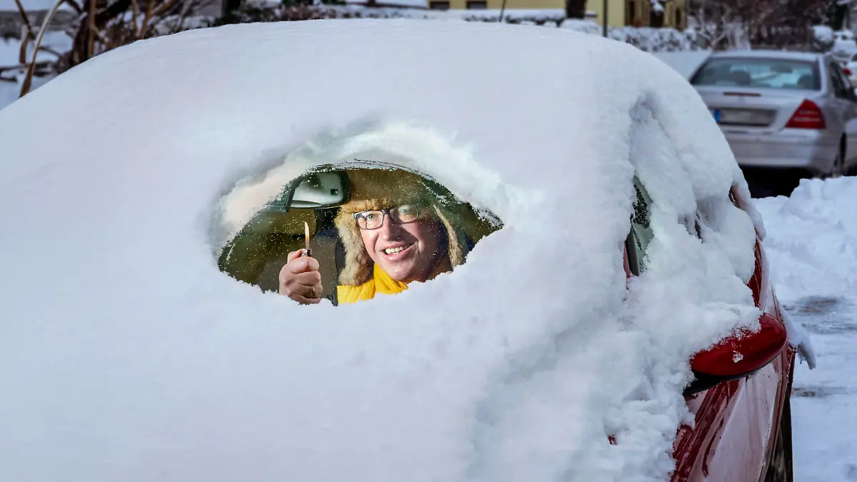 News Bilder des Tages Autofahrer befreit mit Feuerzeug Windschutzscheibe von Schnee, München, Dezember 2023 Deutschland,