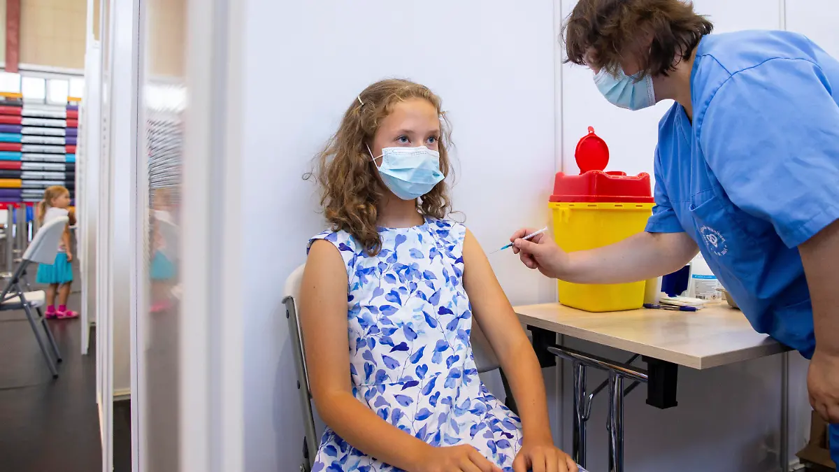 29.07.2021, Estland, Tartu: Ein medizinischer Mitarbeiter verabreicht der 13-jährigen Gloria Raudjarv eine Impfung gegen das Coronavirus in einem Impfzentrum in einer Sporthalle. In Estlands zweitgrößte Stadt Tartu macht man rasche Fortschritte bei der Impfung von Kindern und Jugendlichen im Alter von 12 bis 17 Jahren vor Beginn des Schuljahres im September. Etwa die Hälfte der Teenager der Stadt hat bereits ihre erste Impfung erhalten, und die örtlichen Gesundheitsbehörden sind zuversichtlich, dass sie in den kommenden 30 Tagen eine Rate von 70 Prozent erreichen werden. Foto: Raul Mee/AP/dpa +++ dpa-Bildfunk +++