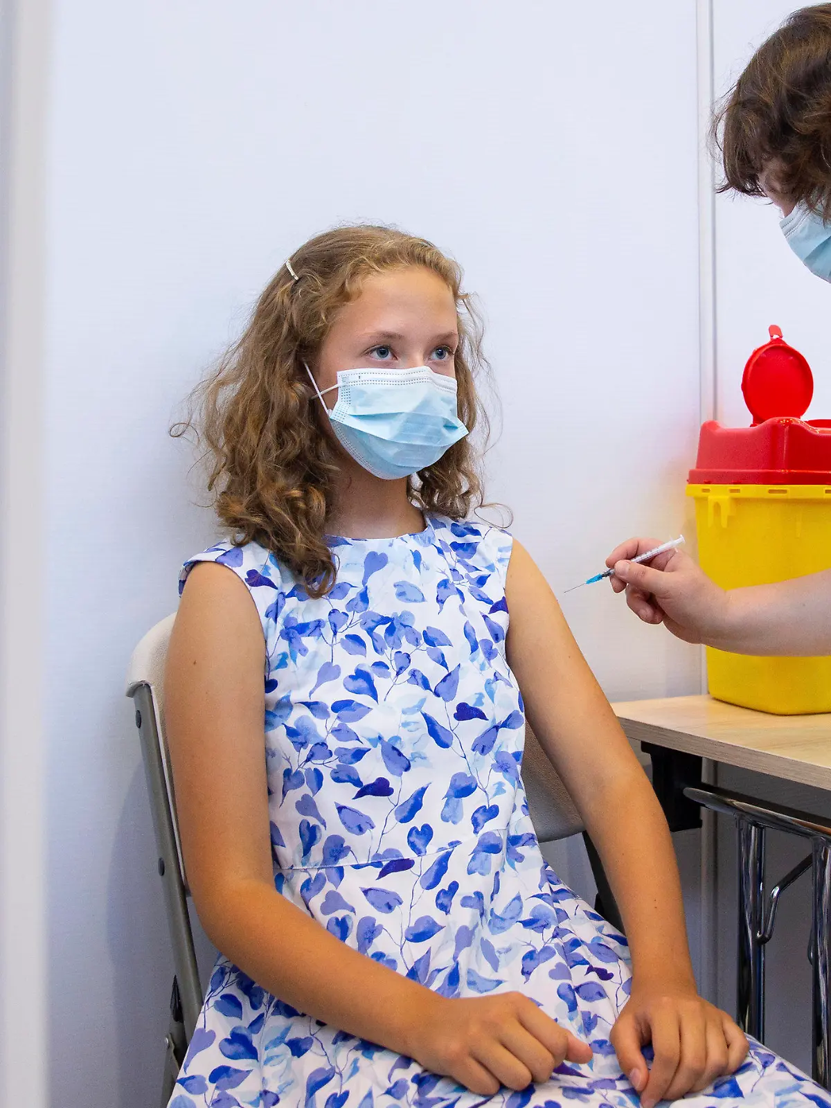 29.07.2021, Estland, Tartu: Ein medizinischer Mitarbeiter verabreicht der 13-jährigen Gloria Raudjarv eine Impfung gegen das Coronavirus in einem Impfzentrum in einer Sporthalle. In Estlands zweitgrößte Stadt Tartu macht man rasche Fortschritte bei der Impfung von Kindern und Jugendlichen im Alter von 12 bis 17 Jahren vor Beginn des Schuljahres im September. Etwa die Hälfte der Teenager der Stadt hat bereits ihre erste Impfung erhalten, und die örtlichen Gesundheitsbehörden sind zuversichtlich, dass sie in den kommenden 30 Tagen eine Rate von 70 Prozent erreichen werden. Foto: Raul Mee/AP/dpa +++ dpa-Bildfunk +++