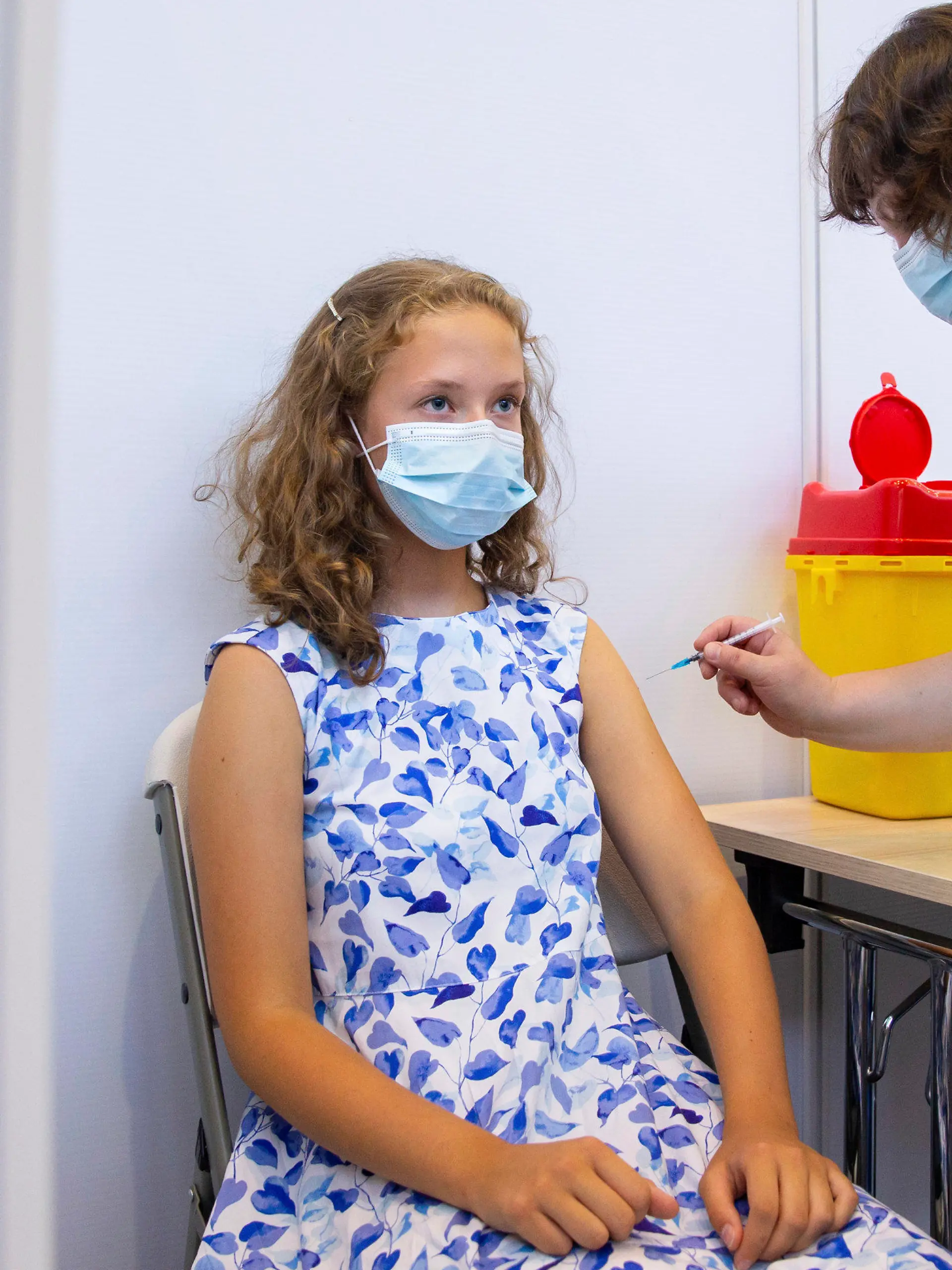 29.07.2021, Estland, Tartu: Ein medizinischer Mitarbeiter verabreicht der 13-jährigen Gloria Raudjarv eine Impfung gegen das Coronavirus in einem Impfzentrum in einer Sporthalle. In Estlands zweitgrößte Stadt Tartu macht man rasche Fortschritte bei der Impfung von Kindern und Jugendlichen im Alter von 12 bis 17 Jahren vor Beginn des Schuljahres im September. Etwa die Hälfte der Teenager der Stadt hat bereits ihre erste Impfung erhalten, und die örtlichen Gesundheitsbehörden sind zuversichtlich, dass sie in den kommenden 30 Tagen eine Rate von 70 Prozent erreichen werden. Foto: Raul Mee/AP/dpa +++ dpa-Bildfunk +++