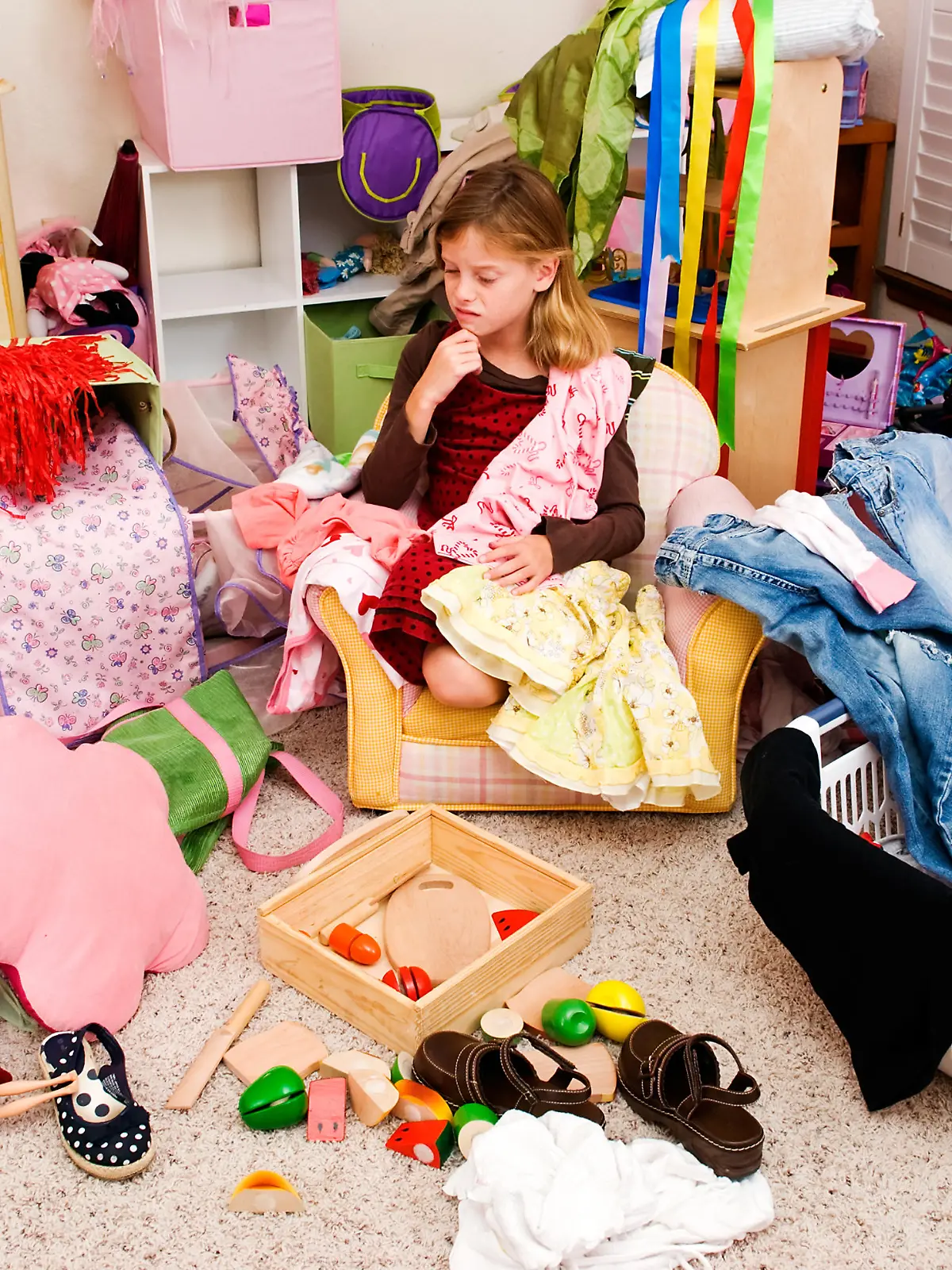 Mädchen sitzt in ihrem unordentlichen Kinderzimmer