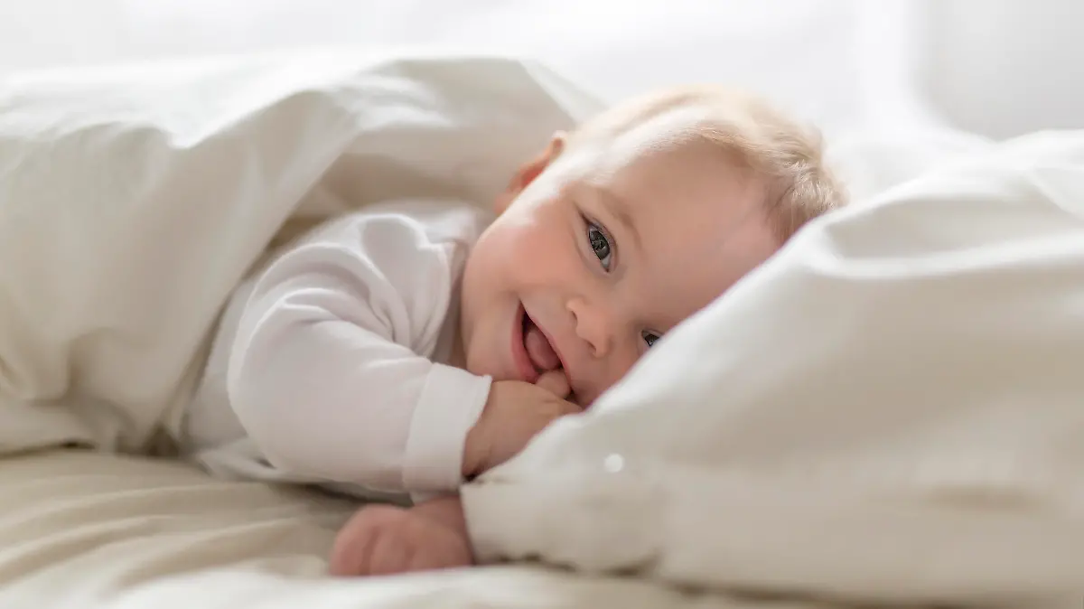 Baby liegt im Bett und lächelt
