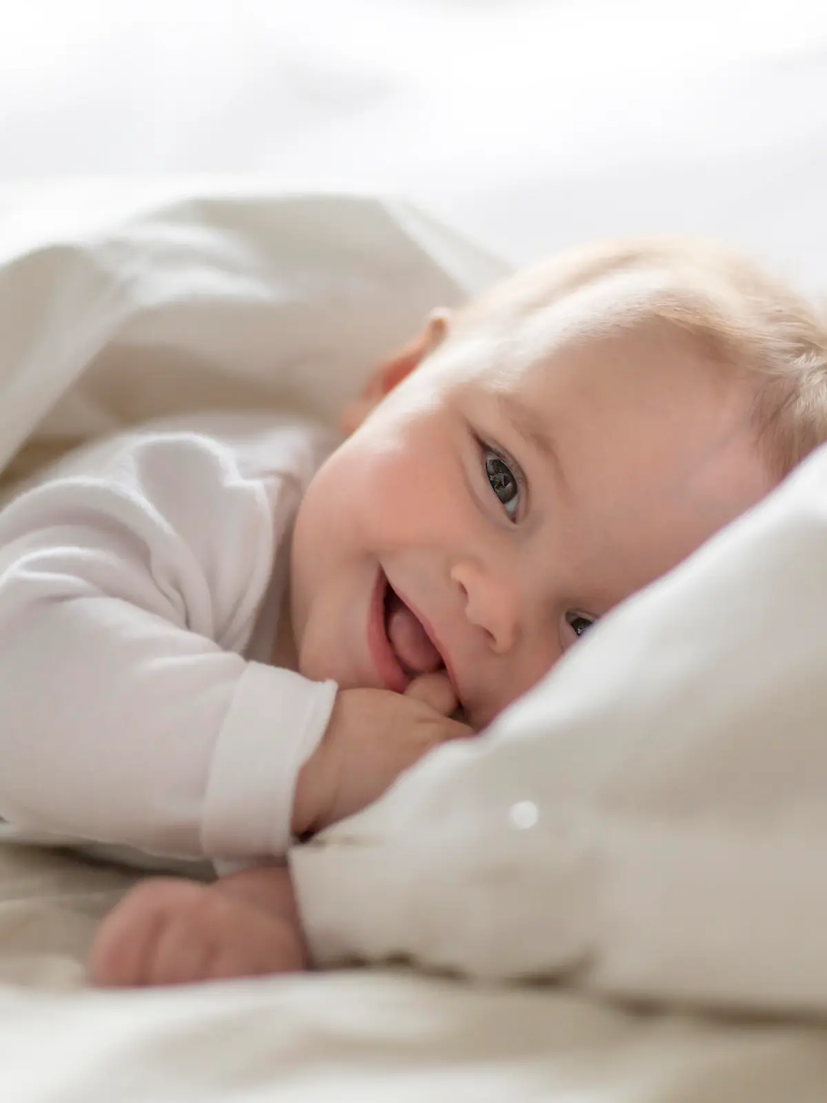Baby liegt im Bett und lächelt