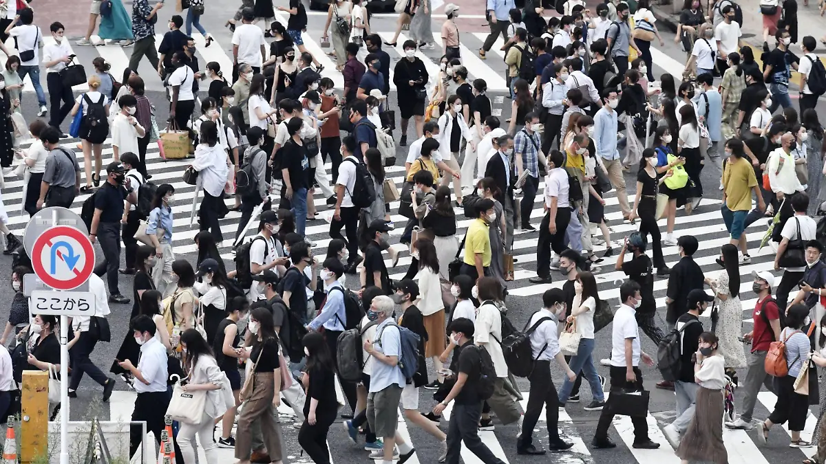 30.07.2021, Japan, Tokio: Passanten mit Mund-Nasen-Schutz gehen über eine belebte Kreuzung im Stadtteil Shibuya. Japan hat wegen stark gestiegener Corona-Infektionen den Notstand für die Olympia-Stadt Tokio abermals verlängert und auf weitere Präfekturen ausgeweitet. Foto: --/kyodo/dpa +++ dpa-Bildfunk +++