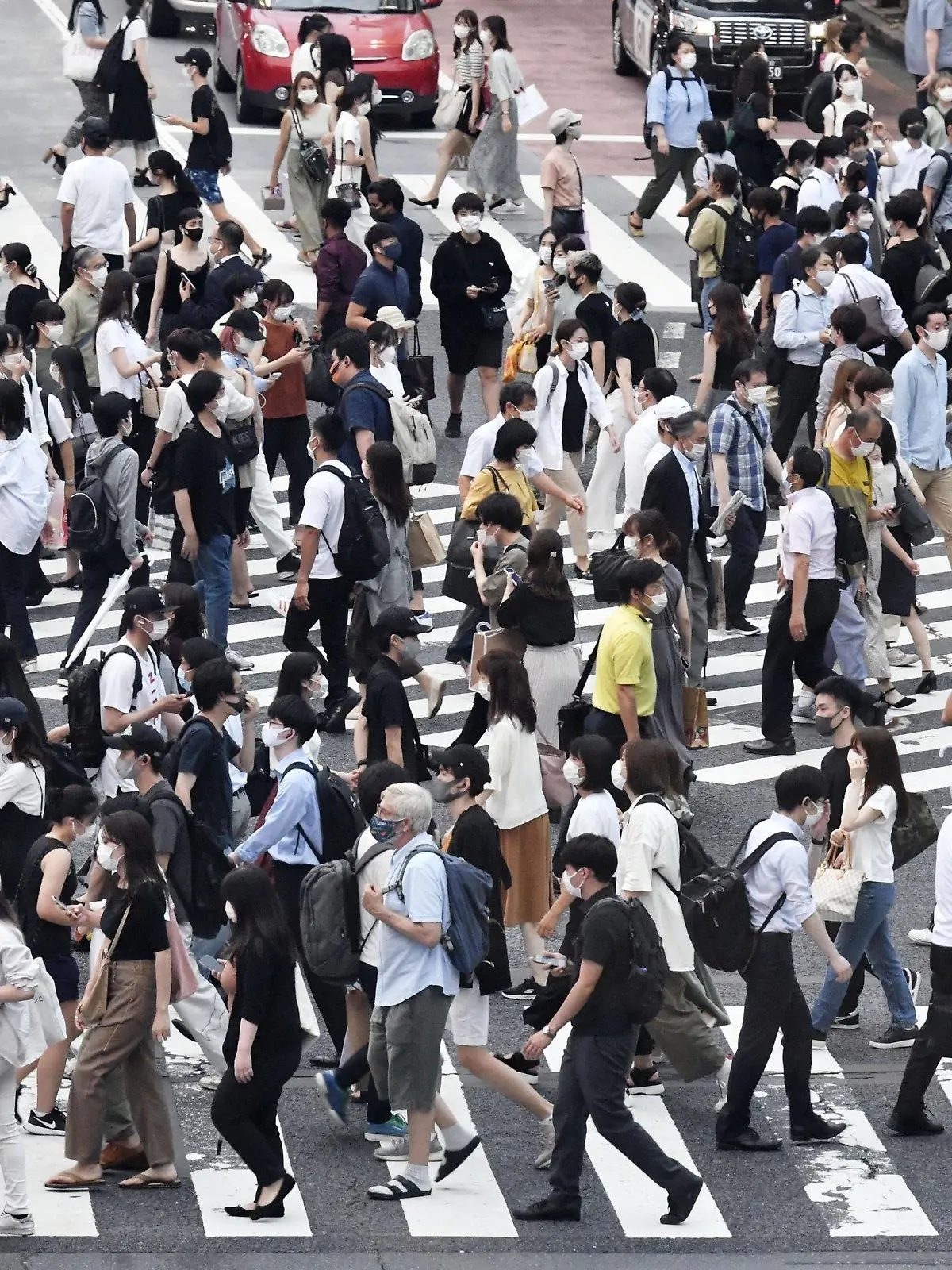 30.07.2021, Japan, Tokio: Passanten mit Mund-Nasen-Schutz gehen über eine belebte Kreuzung im Stadtteil Shibuya. Japan hat wegen stark gestiegener Corona-Infektionen den Notstand für die Olympia-Stadt Tokio abermals verlängert und auf weitere Präfekturen ausgeweitet. Foto: --/kyodo/dpa +++ dpa-Bildfunk +++