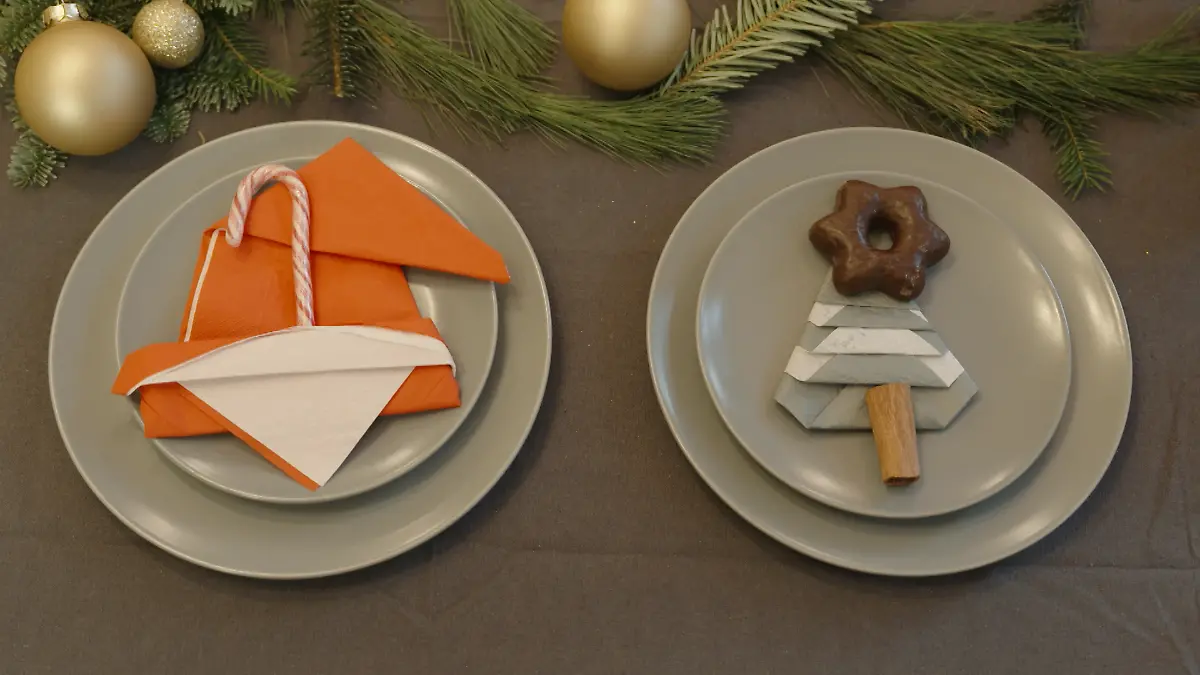 Eine rote Serviette gefaltet als Weihnachtsmütze und eine grüne als Tannenbaum.