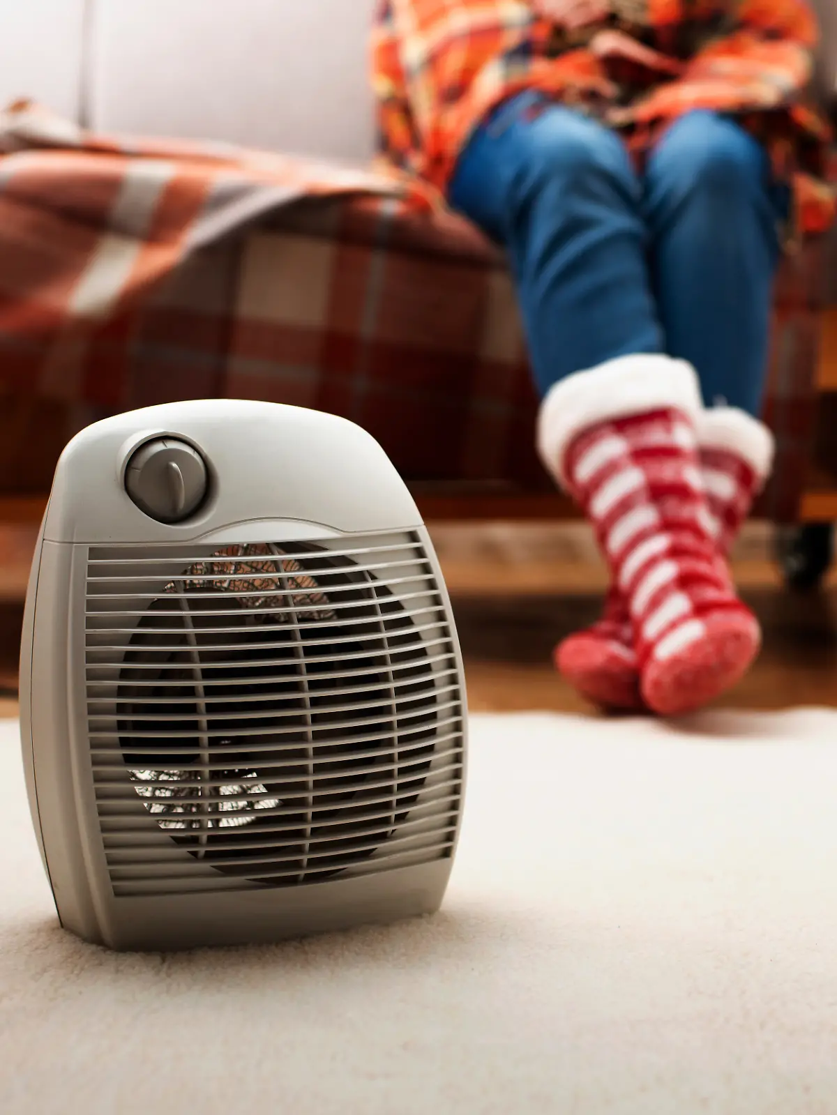 Frau mit Kuschelsocken vor Heizlüfter