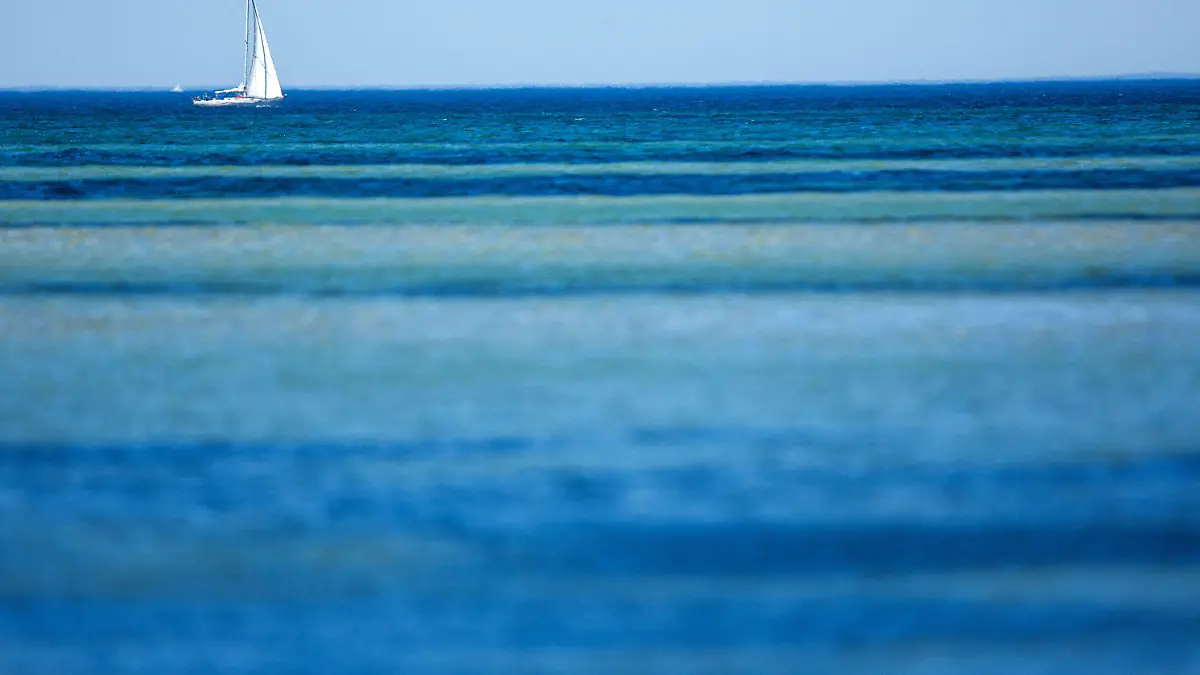 Ein Segelboot kreuzt am 02.07.2015 auf der Ostsee vor dem Strand von Timmendorf (Mecklenburg-Vorpommern) auf der Insel Poel. Nach langem Warten ist der Sommer endlich an der Ostseeküste angekommen. Bei Temperaturen von bis zu 30 Grad füllen sich die Strände und Urlaubsorte an der Küste in Mecklenburg-Vorpommern. Foto: Jens Büttner/dpa +++(c) dpa - Bildfunk+++