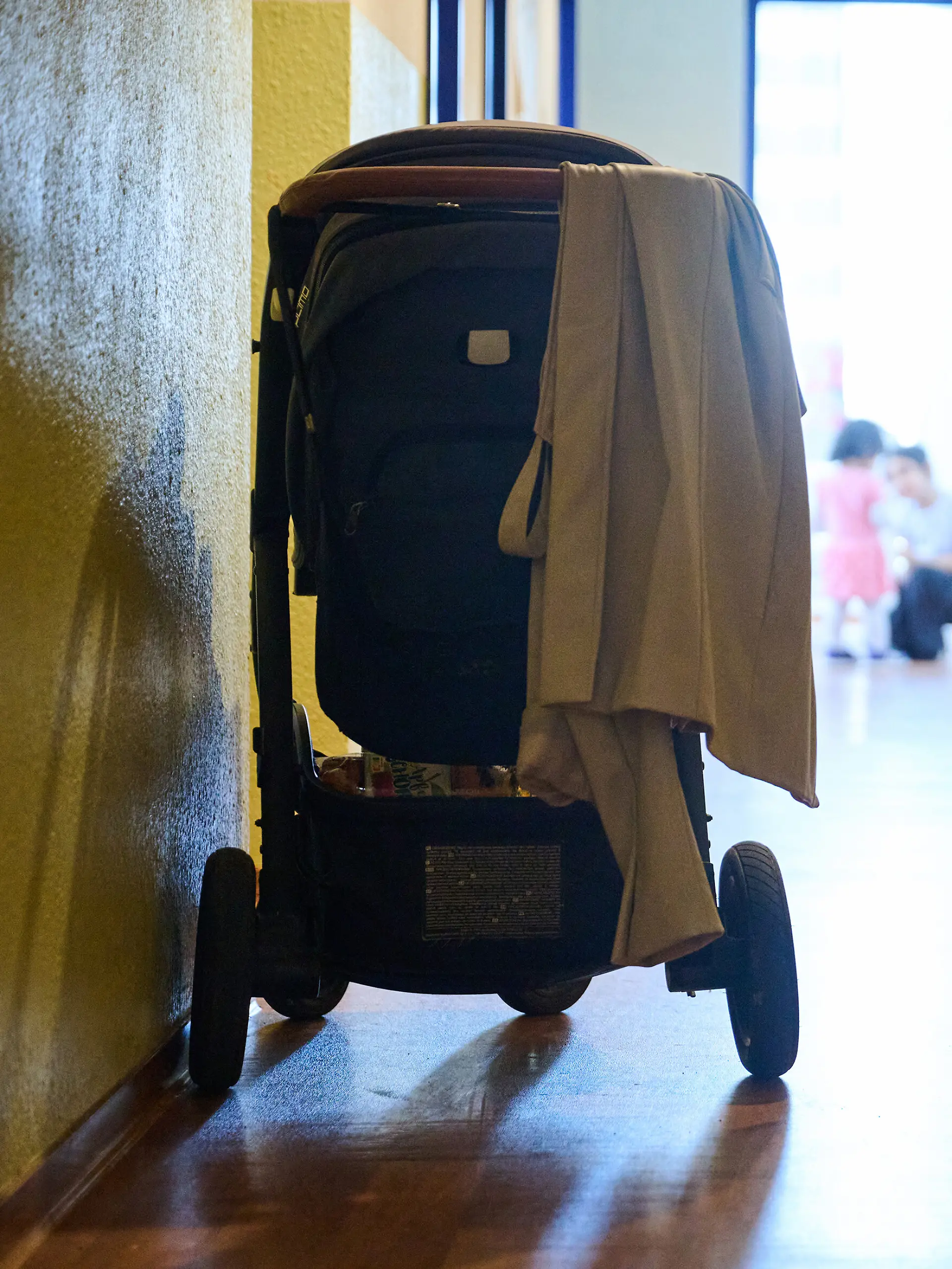 In einem Flur eines Frauenhauses steht ein Kinderwagen, während zwei Kinder am Ende des Flurs spielen.