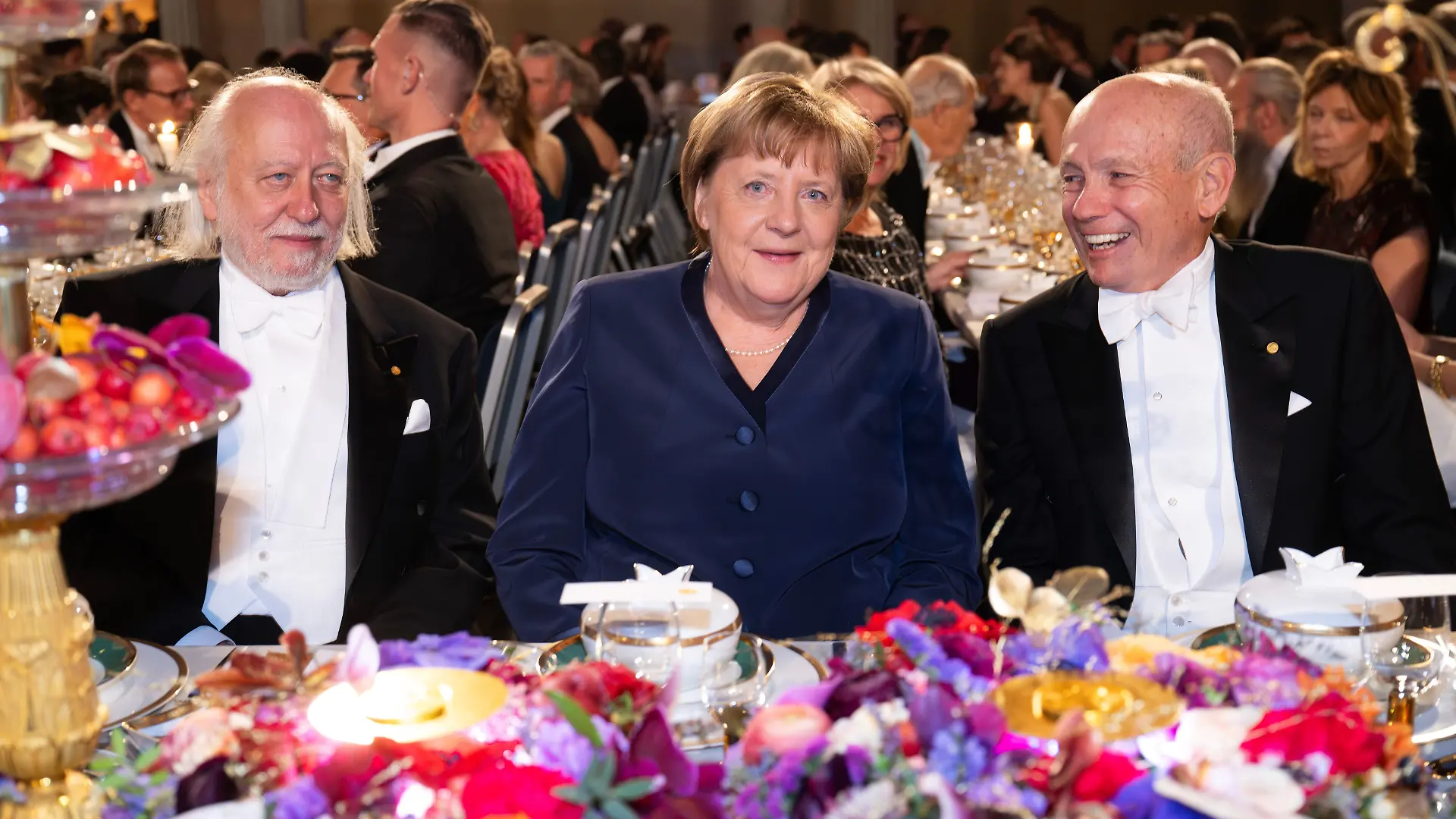 Ex-Bundeskanzlerin Angela Merkel sitzt zwischen dem Literaturnobelpreisträger Laszlo Krasznahorkai aus Ungarn und Wirtschaftsnobelpreisträger Peter Howitt.
