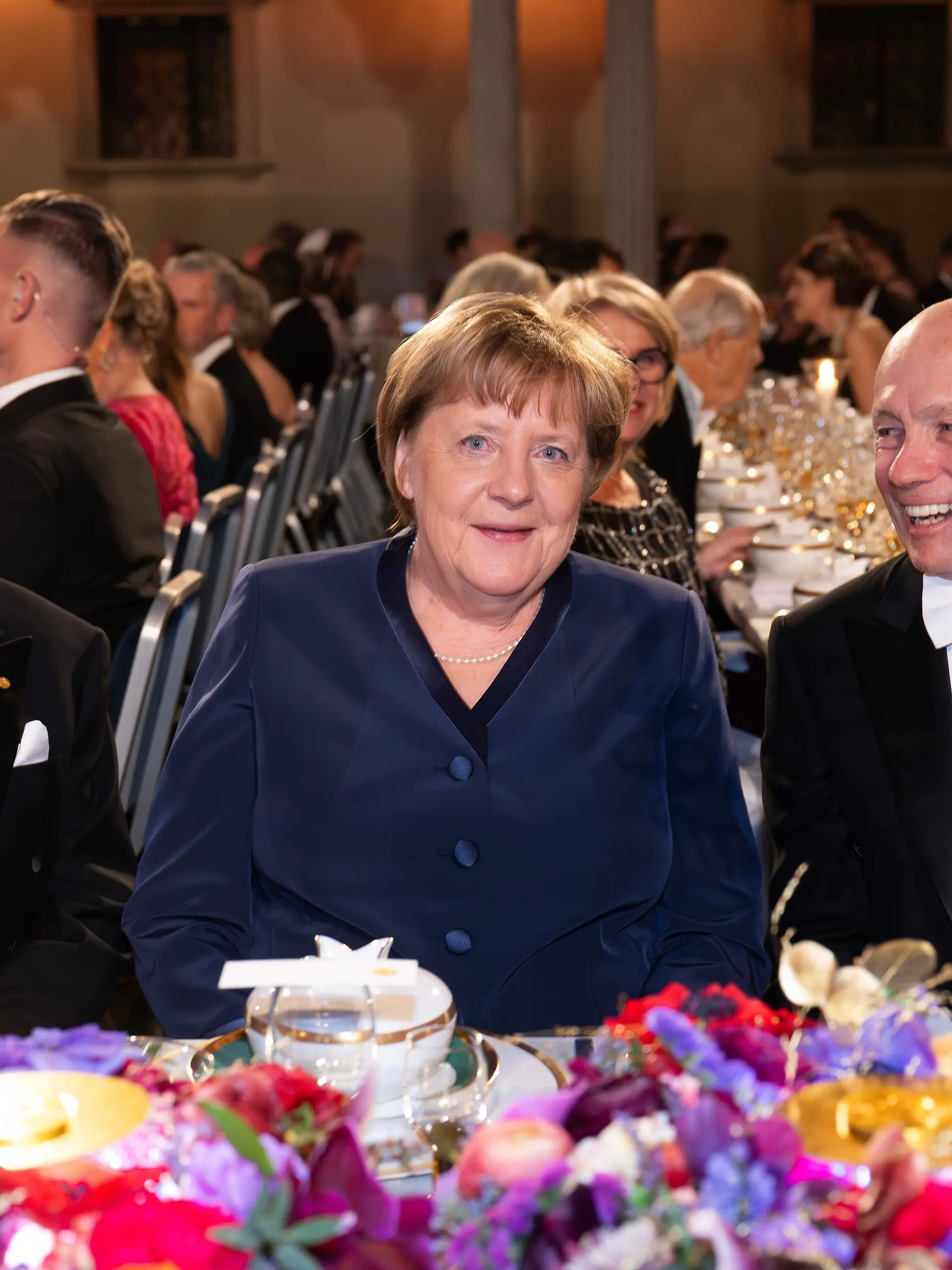 Ex-Bundeskanzlerin Angela Merkel sitzt zwischen dem Literaturnobelpreisträger Laszlo Krasznahorkai aus Ungarn und Wirtschaftsnobelpreisträger Peter Howitt.