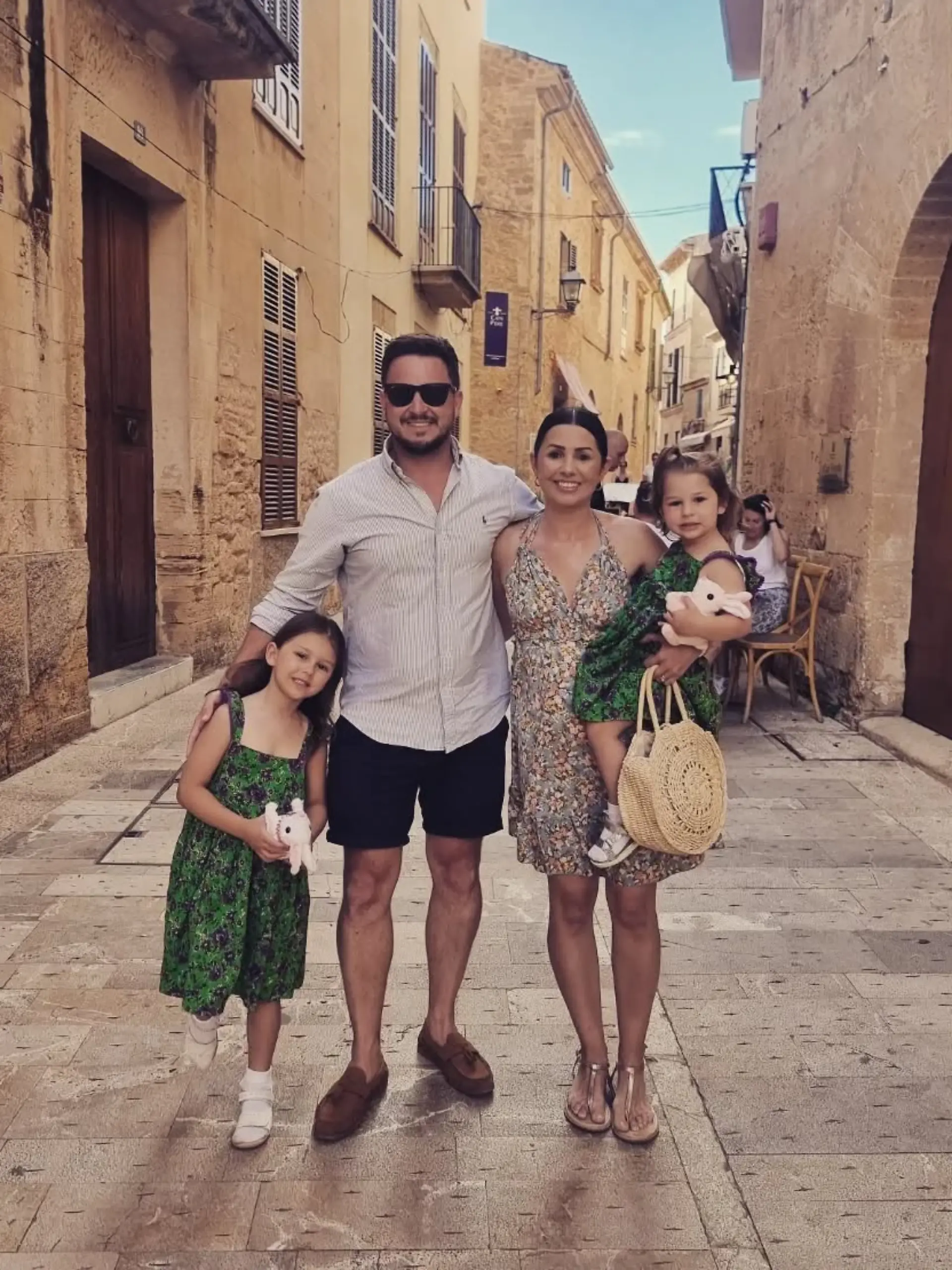 Mallorca (Spanien): Die Vierköpfige Familie Dunion im Urlaub. Sie stehen in einer Gasse in Alcúdia und lächeln in die Kamera.