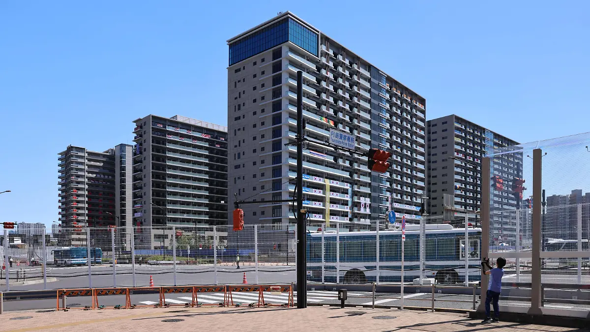July 21, 2021, Tokyo, Japan: A woman takes pictures of the Olympic Village in Harumi as busses drive in and out..Usually the heart piece of Olympic Games, Olympische Spiele, Olympia, OS the Tokyo 2020 Olympic village in Harumi is secured behind tall metal fences with military and police on patrol duty and check points with roadblocks. Inside, athletes and other members of the Olympic teams have to adhere to strict protocols to minimize the risk of contracting Sars-CoV-2-Coronavirus. Tokyo Japan - ZUMAs197 0126597738st Copyright: xStanislavxKogikux