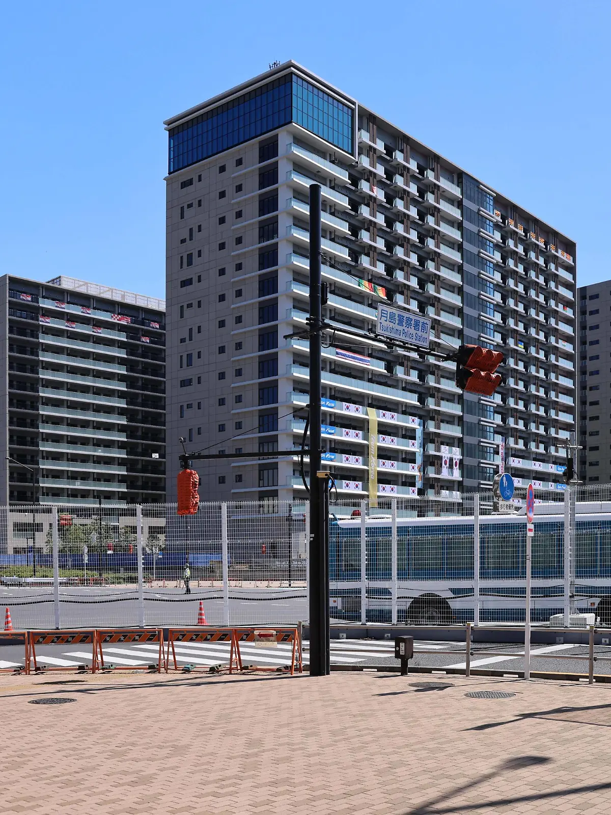 July 21, 2021, Tokyo, Japan: A woman takes pictures of the Olympic Village in Harumi as busses drive in and out..Usually the heart piece of Olympic Games, Olympische Spiele, Olympia, OS the Tokyo 2020 Olympic village in Harumi is secured behind tall metal fences with military and police on patrol duty and check points with roadblocks. Inside, athletes and other members of the Olympic teams have to adhere to strict protocols to minimize the risk of contracting Sars-CoV-2-Coronavirus. Tokyo Japan - ZUMAs197 0126597738st Copyright: xStanislavxKogikux 