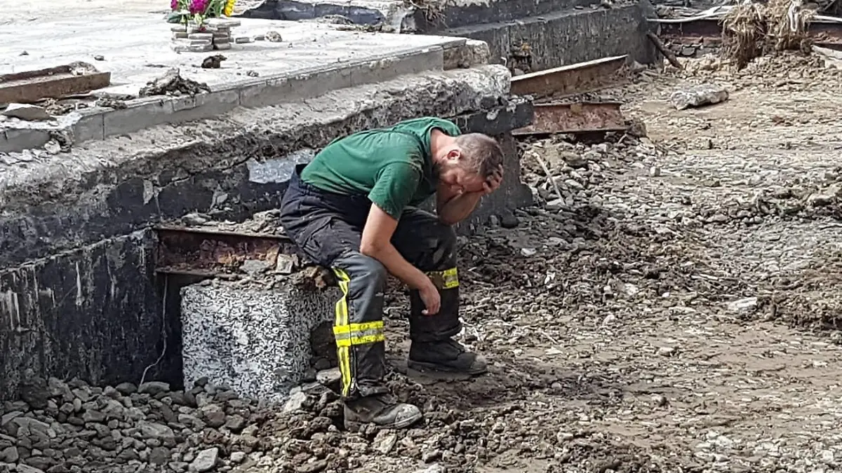 Feuerwehrmann steht vor einem zerstörten Haus in Ahrbrück.