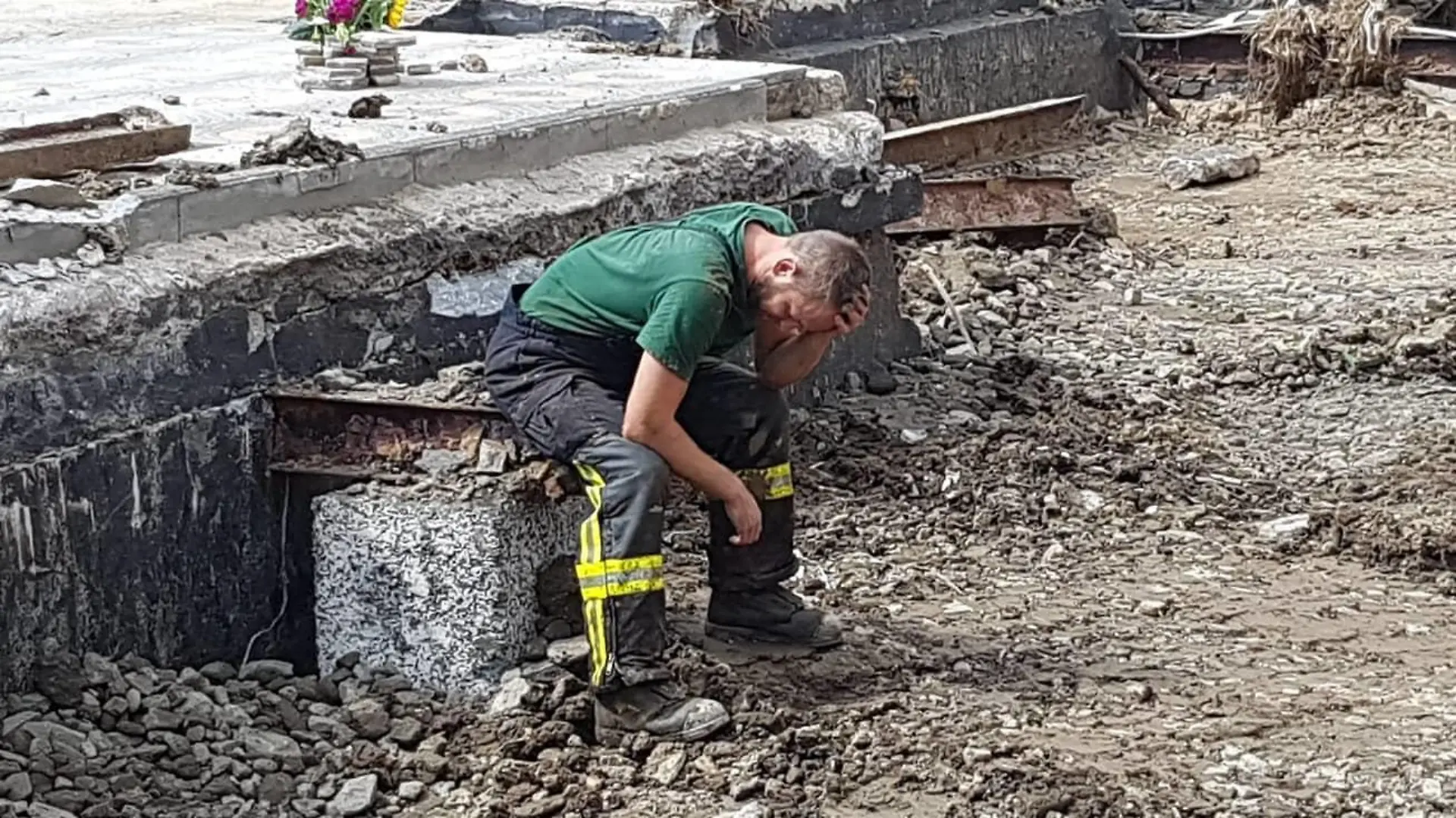 Feuerwehrmann steht vor einem zerstörten Haus in Ahrbrück.