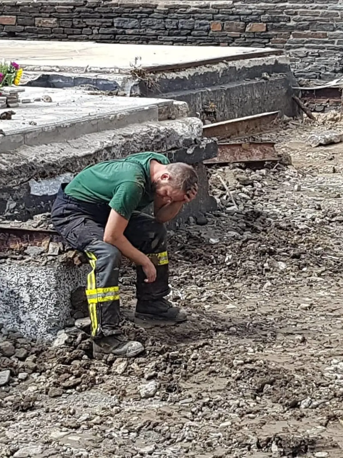 Feuerwehrmann steht vor einem zerstörten Haus in Ahrbrück.