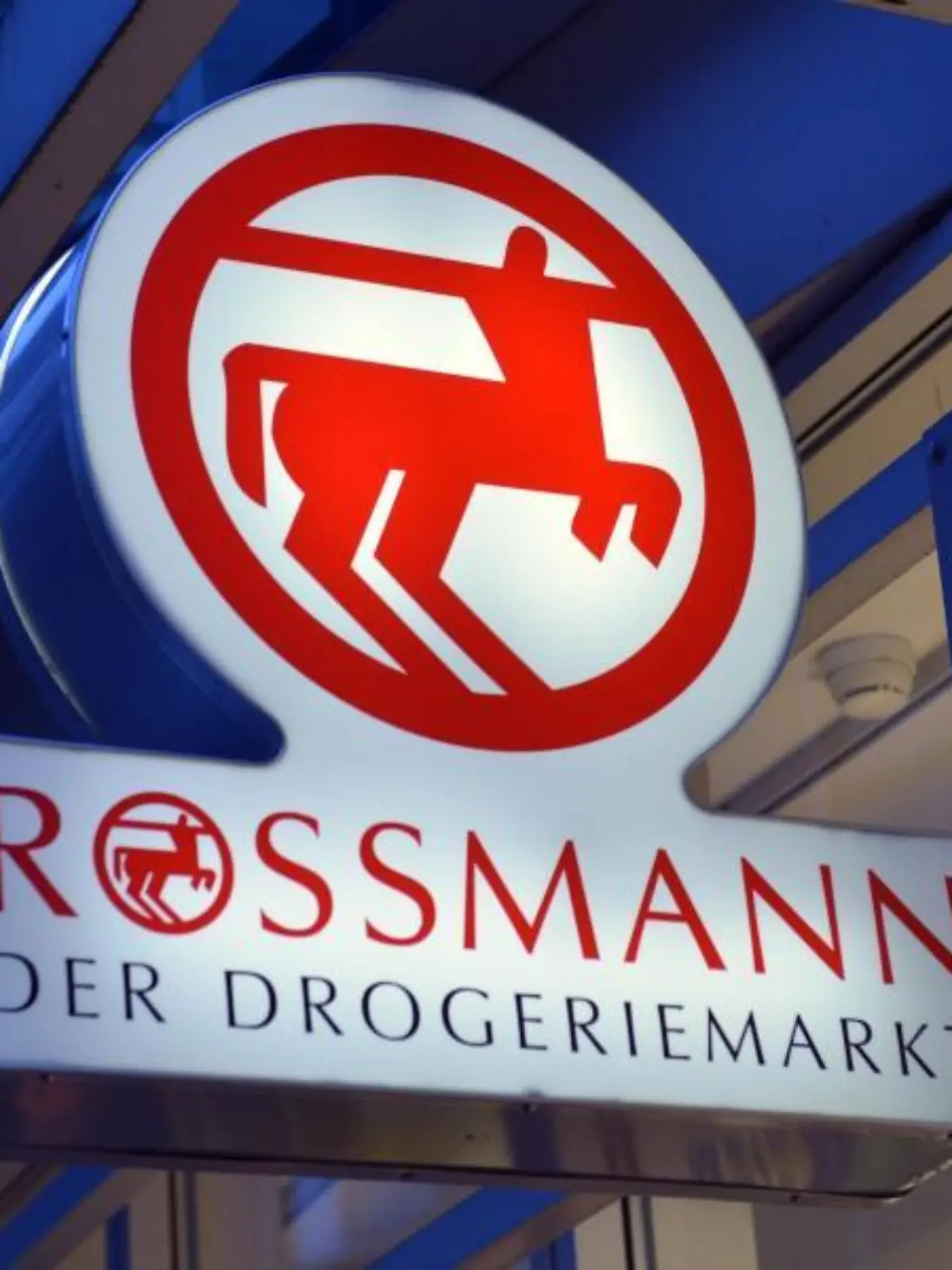 Ein Schild mit dem Logo von Rossmann leuchtet an einer Filiale