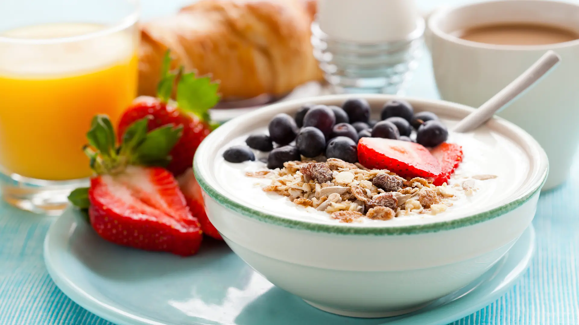 Ein gesundes Frühstück mit Müsli mit Joghurt, Obst, gekochtem Ei und Orangensaft