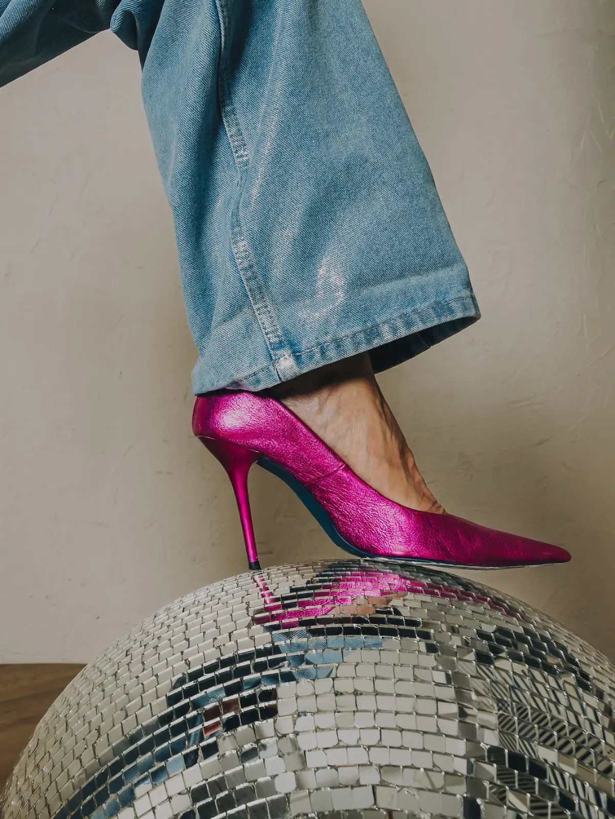 Eine Frau trägt eine Jeans und pinke High-Heels.