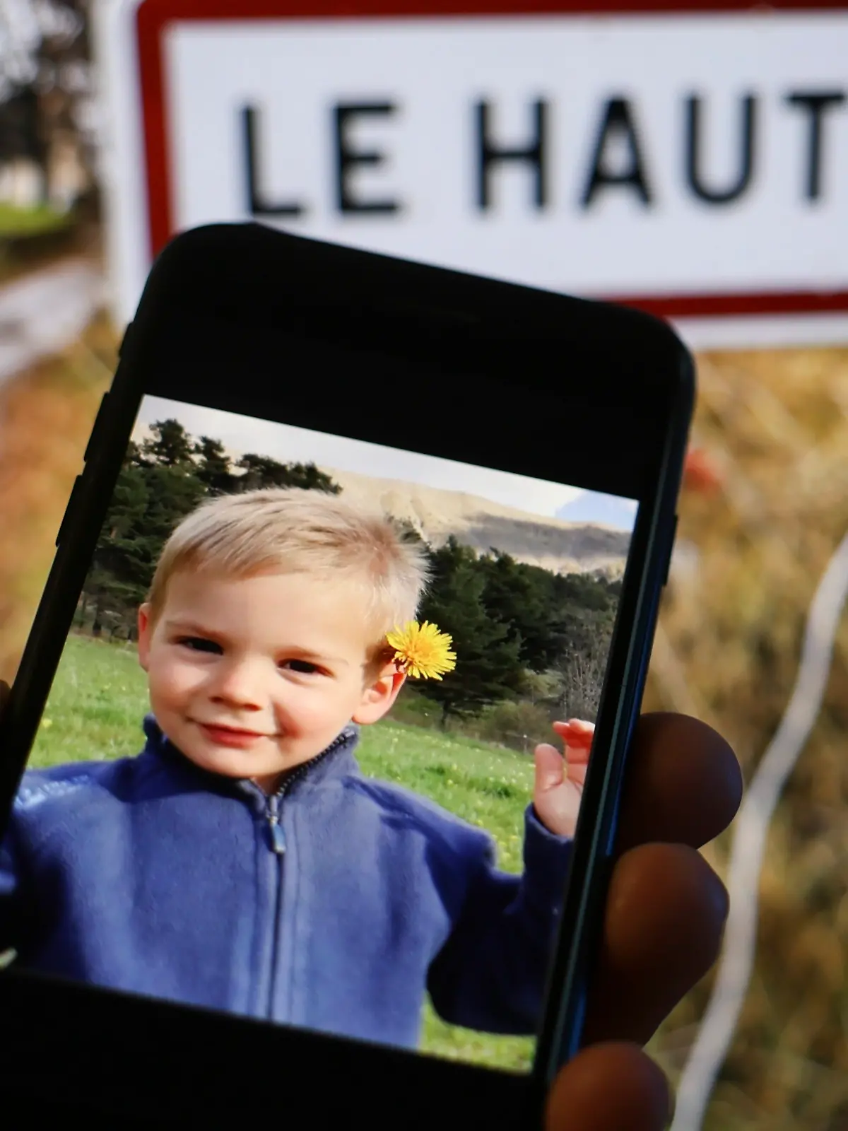 Foto von Émile auf einem Handy vor dem Ortsschild von Le Vernet, wo er verschwand 