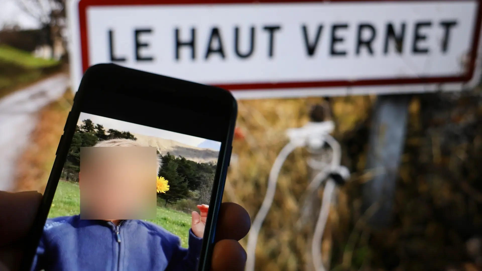Foto von Émile auf einem Handy vor dem Ortsschild von Le Vernet, wo er verschwand 