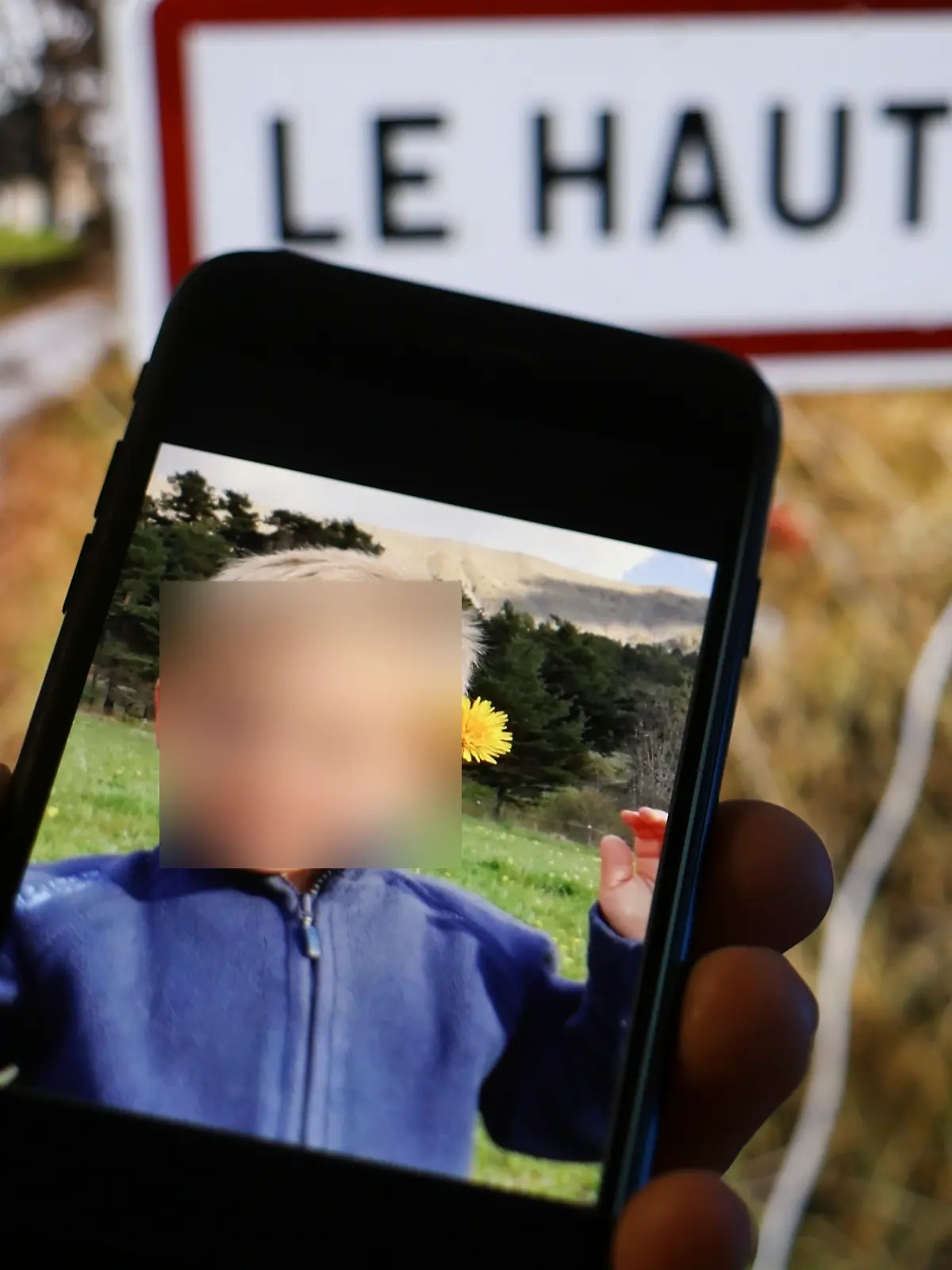 Foto von Émile auf einem Handy vor dem Ortsschild von Le Vernet, wo er verschwand 