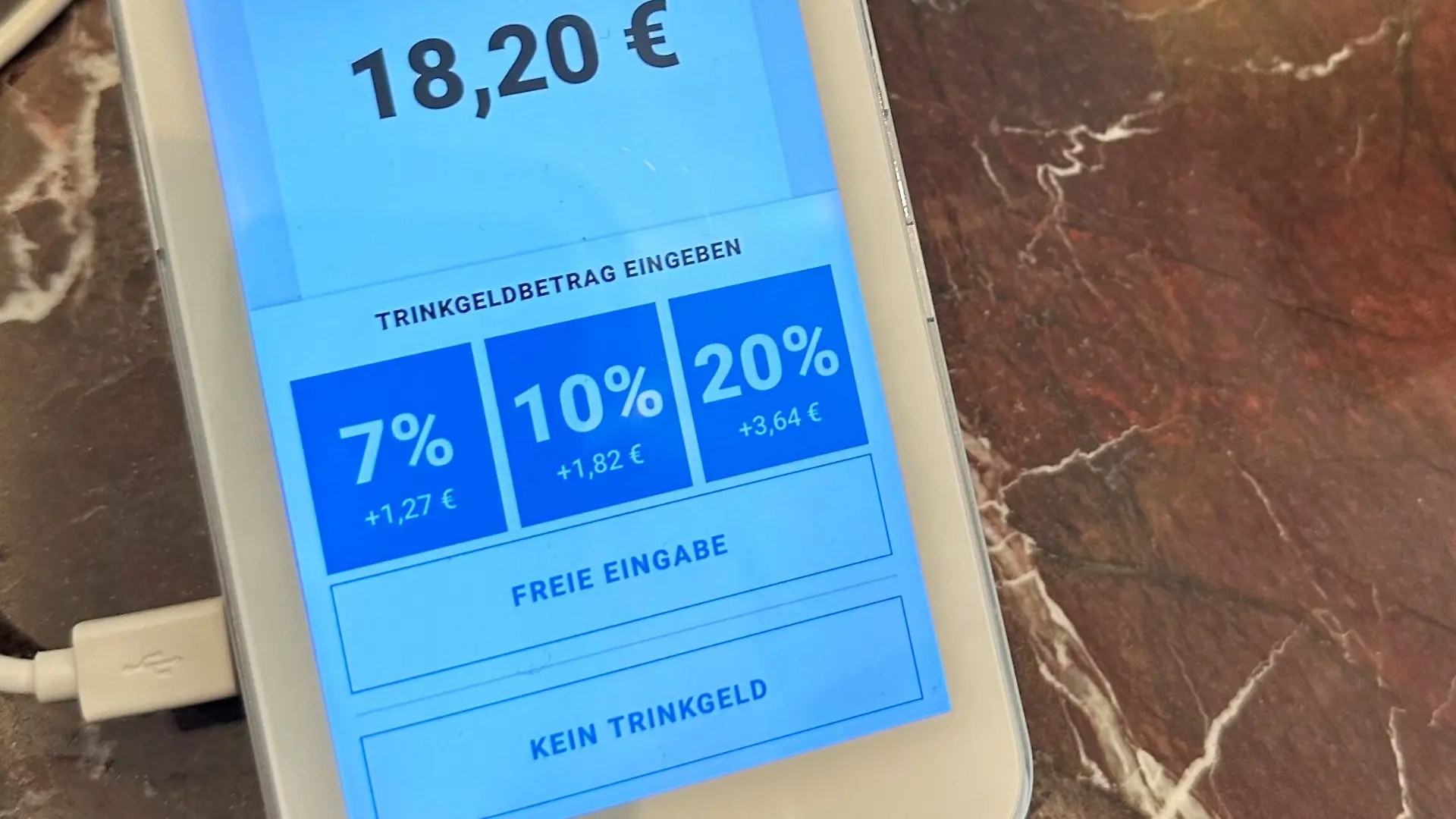 Auf dem Display eines Kartenlesegerätes in einem Café werden anwählbare Trinkgeld-Optionen angezeigt.