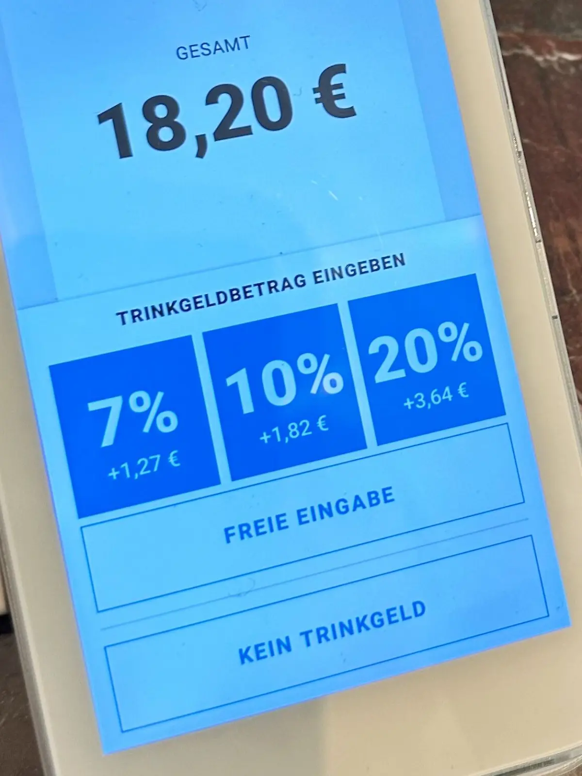 Auf dem Display eines Kartenlesegerätes in einem Café werden anwählbare Trinkgeld-Optionen angezeigt.