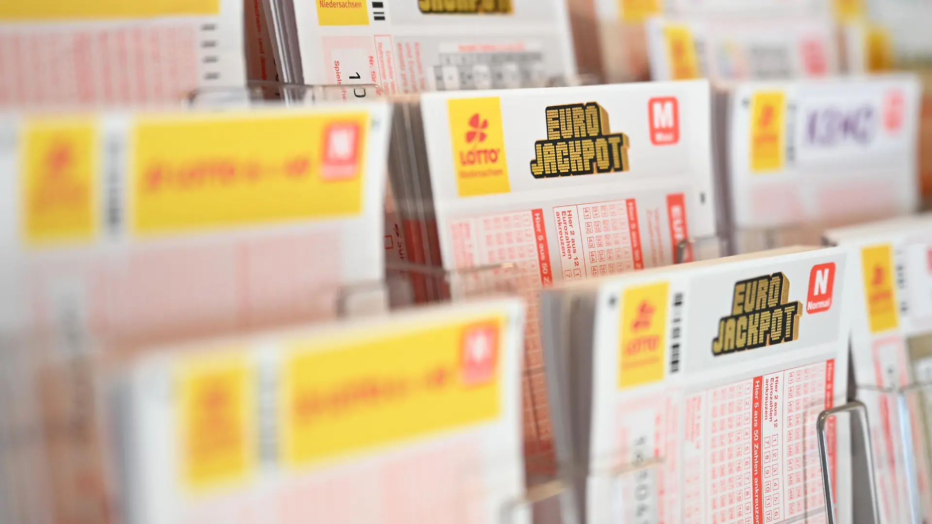 Mehrere Lotto- und Eurojackpot-Spielscheine von Lotto Niedersachsen liegen in einer Auslage.