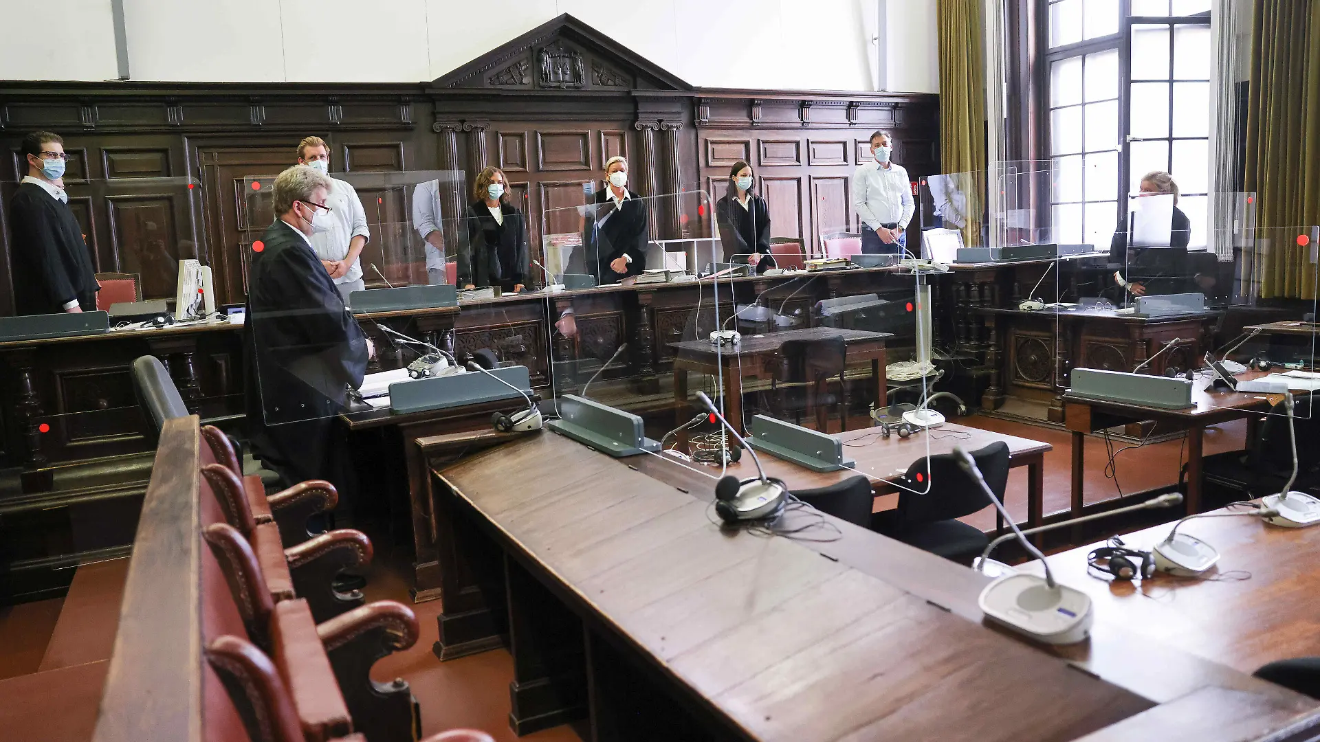 03.08.2021, Hamburg: Jessica Koerner (5.v.l), Vorsitzende Richterin am Landgericht, Peter Jacobi (2.v.l), Anwalt des Angeklagten, und weitere Prozessbeteiligte stehen zu Beginn des Ersten Prozesstages im Sitzungssal im Strafjustizgebäude. Der 29-Jährige Angeklagte soll Anfang Februar 2021 seine damalige Lebensgefährtin tödlich verletzt und am Folgetag seine Mutter mit zahlreichen Messerstichen umgebracht haben. Da der Beschuldigte diese und weitere Taten aufgrund einer psychischen Erkrankung im Zustand der Schuldunfähigkeit begangen hat, handelt es sich um ein Sicherungsverfahren. Foto: Christian Charisius/dpa-Pool/dpa +++ dpa-Bildfunk +++
