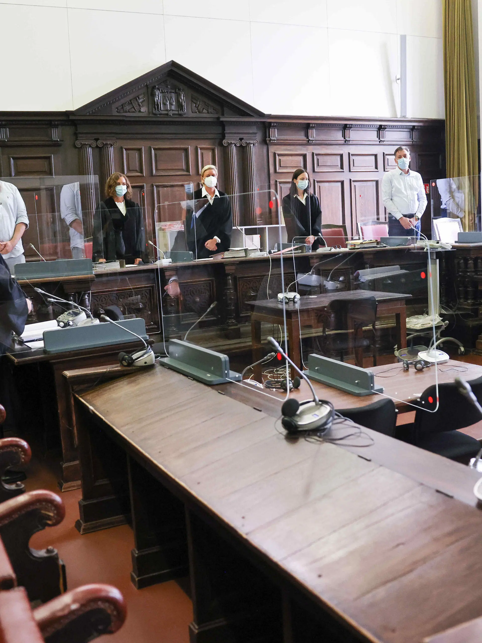 03.08.2021, Hamburg: Jessica Koerner (5.v.l), Vorsitzende Richterin am Landgericht, Peter Jacobi (2.v.l), Anwalt des Angeklagten, und weitere Prozessbeteiligte stehen zu Beginn des Ersten Prozesstages im Sitzungssal im Strafjustizgebäude. Der 29-Jährige Angeklagte soll Anfang Februar 2021 seine damalige Lebensgefährtin tödlich verletzt und am Folgetag seine Mutter mit zahlreichen Messerstichen umgebracht haben. Da der Beschuldigte diese und weitere Taten aufgrund einer psychischen Erkrankung im Zustand der Schuldunfähigkeit begangen hat, handelt es sich um ein Sicherungsverfahren. Foto: Christian Charisius/dpa-Pool/dpa +++ dpa-Bildfunk +++