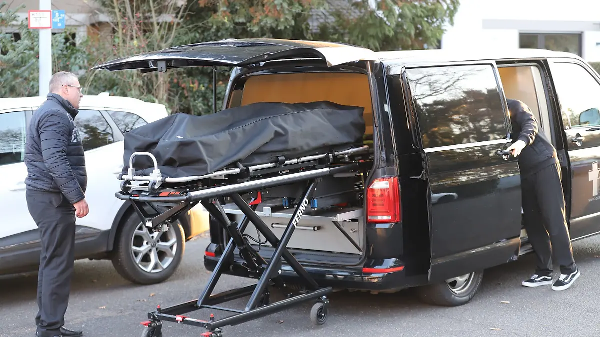 Bestatter laden eine Leiche in einen Leichenwagen.