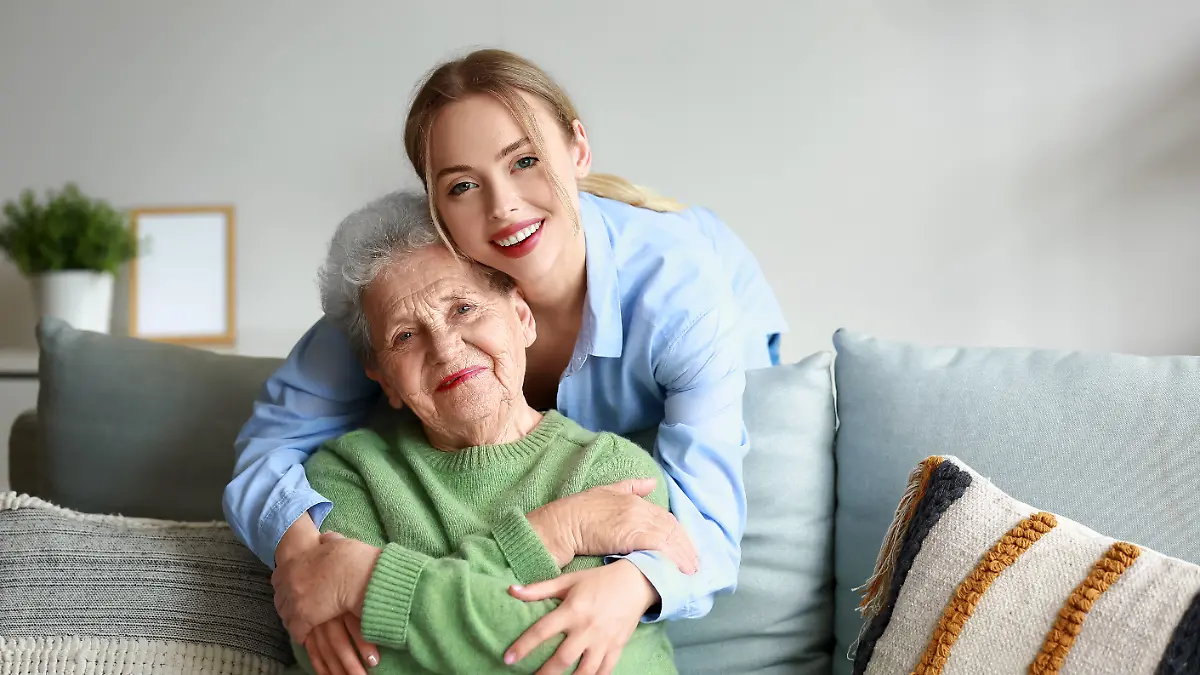 Junge Frau und ihre Großmutter umarmen sich zu Hause
