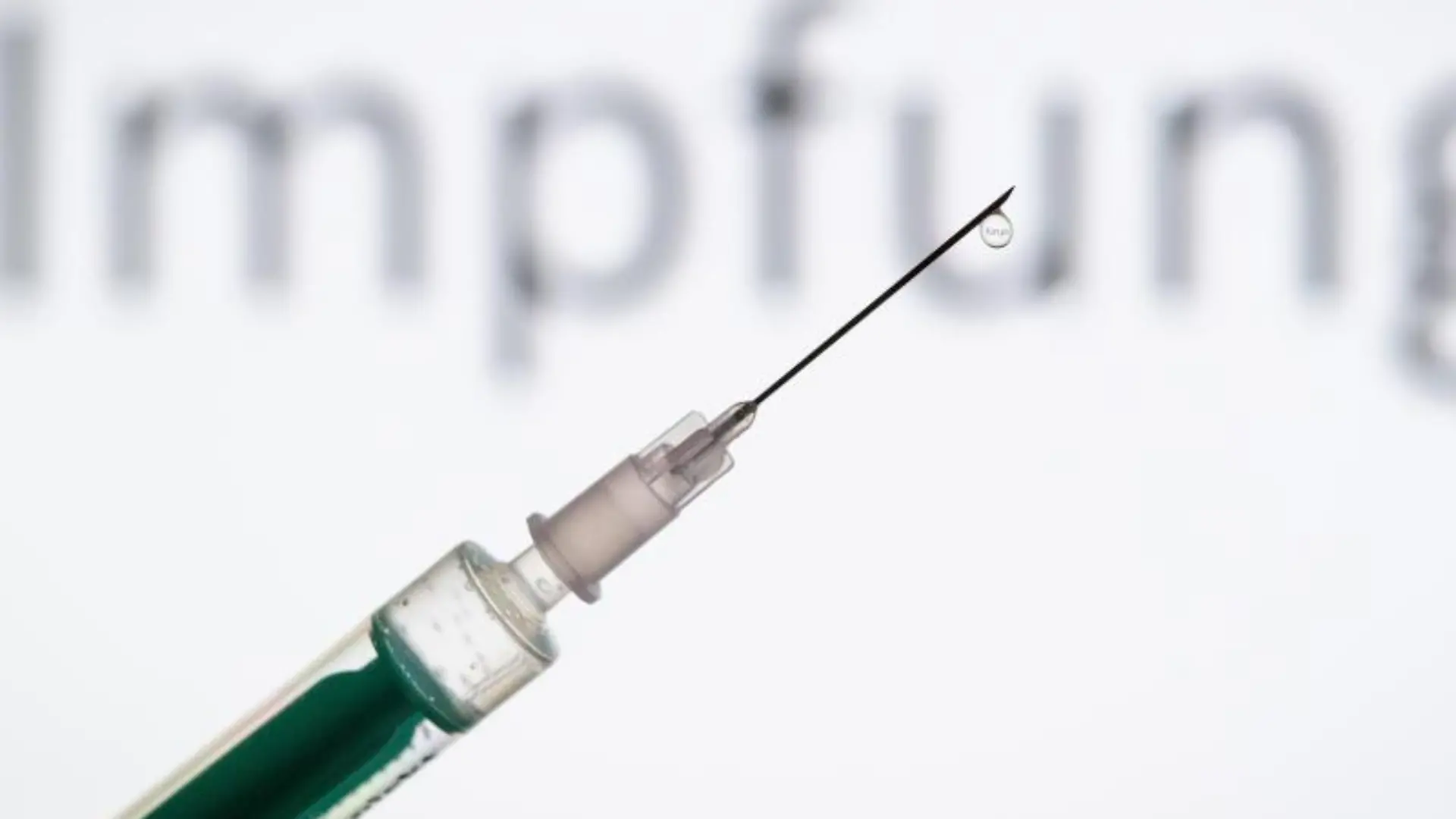 Eine Spritze wird vor den Schriftzug «Impfung» gehalten