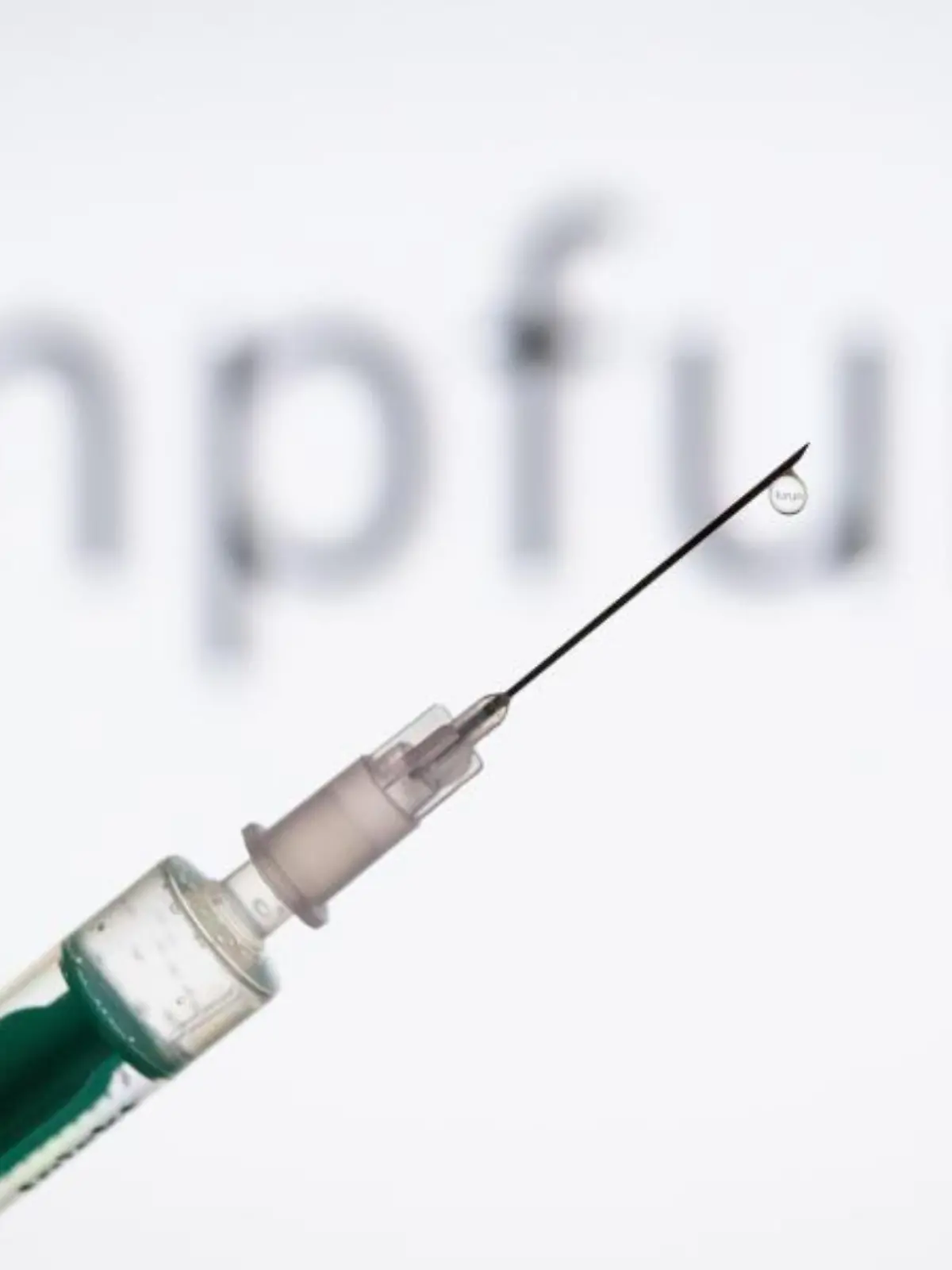 Eine Spritze wird vor den Schriftzug «Impfung» gehalten