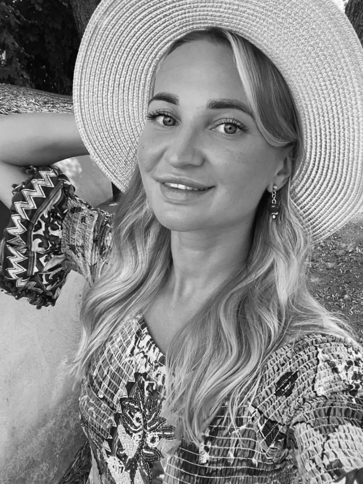 Blonde Frau mit Sonnenhut macht Selfie. 