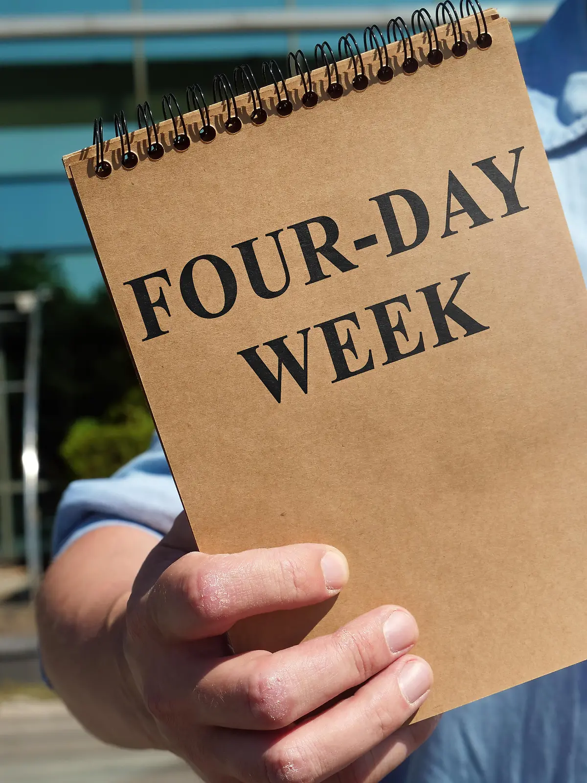 The Man proposes four-day week sign. Notepad in hand.