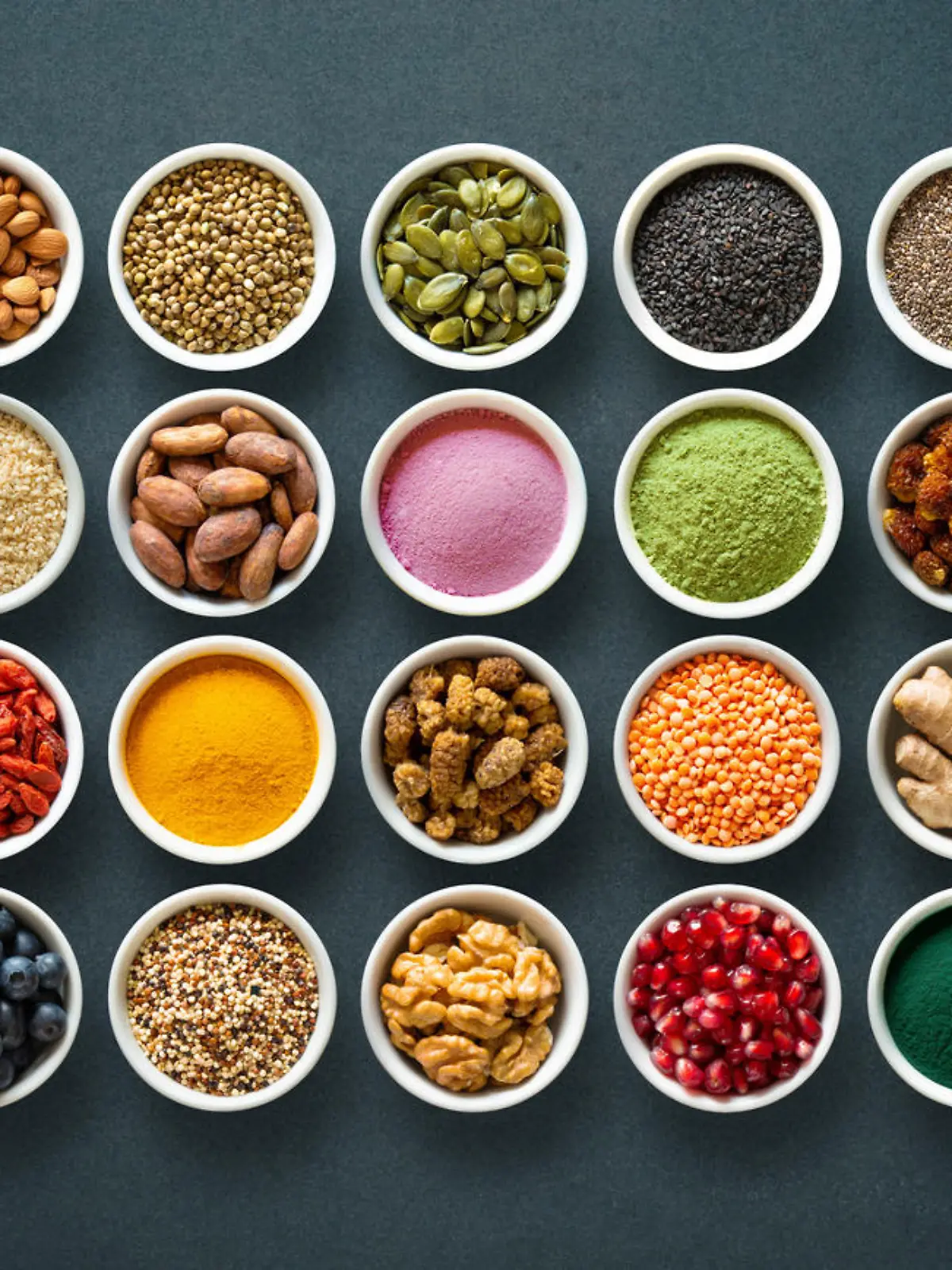 Verschiedene Superfoods in kleinen Gläsern, zum Beispiel Matcha, Spirulina, Quinoa, Goji-Beeren