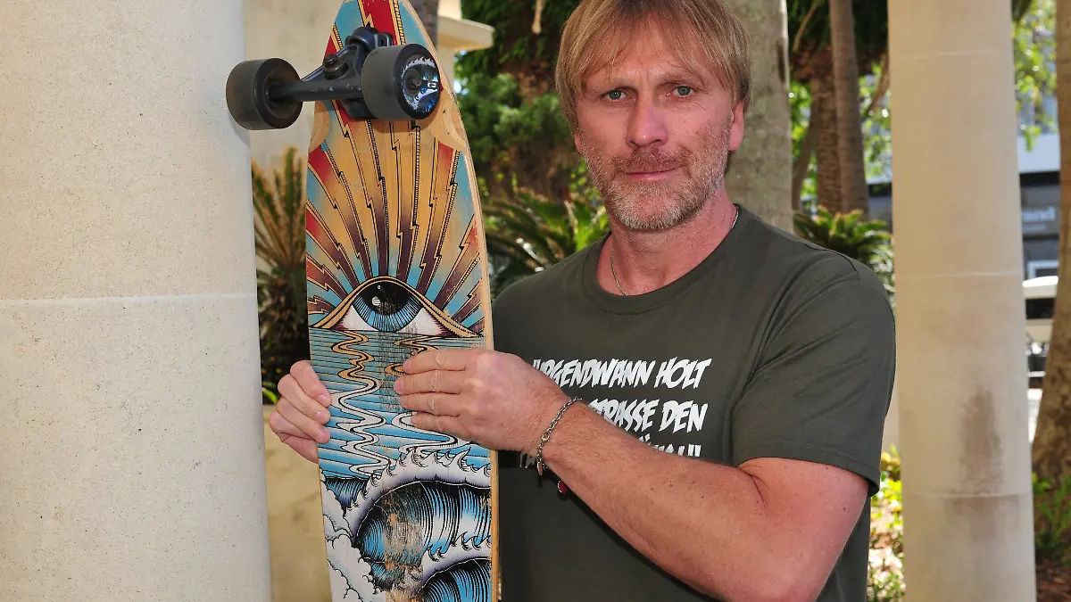 Ansgar Brinkmann nimmt einen Longboard und eine Armbandkette mit