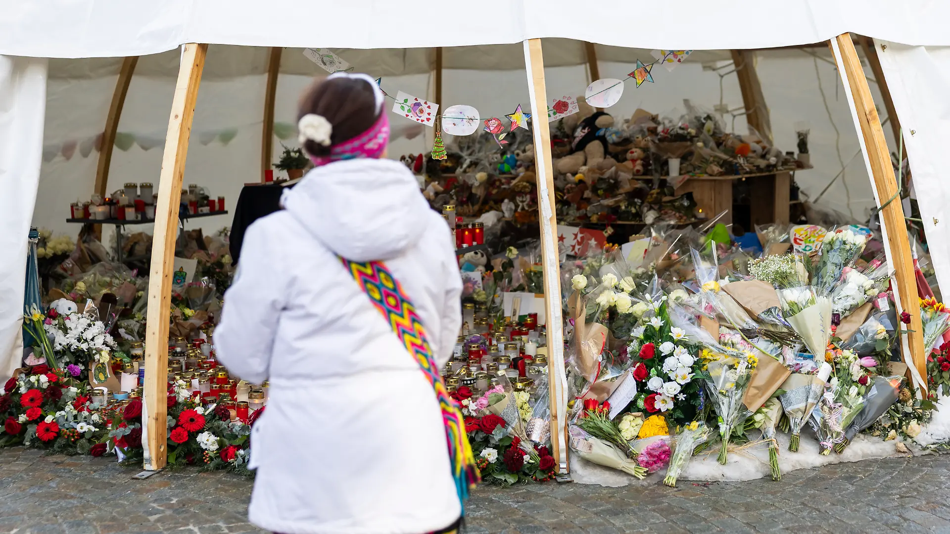 Blumen und Kerzen am Unglücksort zeugen von der Trauer der Menschen um die Opfer des Silvester-Dramas von Crans-Montana.