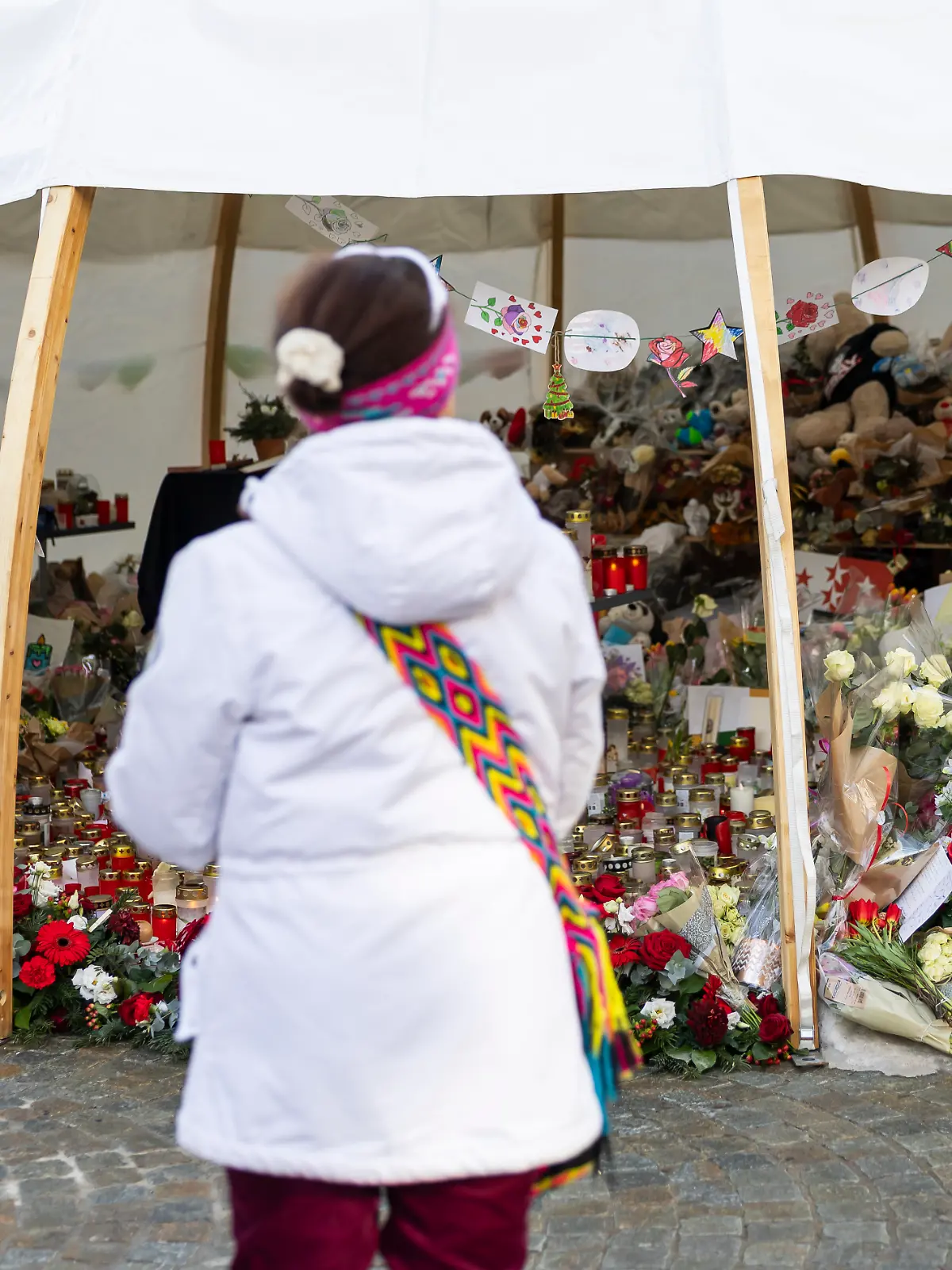 Blumen und Kerzen am Unglücksort zeugen von der Trauer der Menschen um die Opfer des Silvester-Dramas von Crans-Montana. 