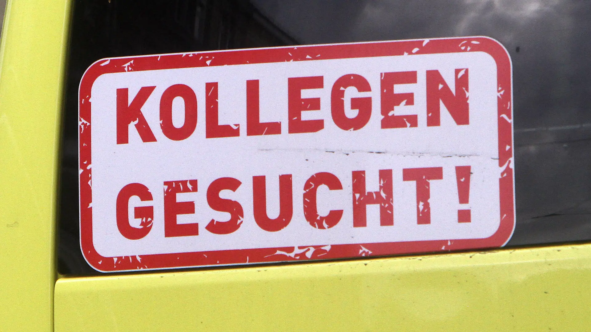 Aufkleber mit Aufschrift Kollegen gesucht klebt am Rückfenster eines Krankentransportwagen s in der Innenstadt von Heidelberg, Baden Württemberg, Deutschland *** Sticker with the inscription Colleagues wanted is stuck on the back window of an ambulance in downtown Heidelberg, Baden Württemberg, Germany