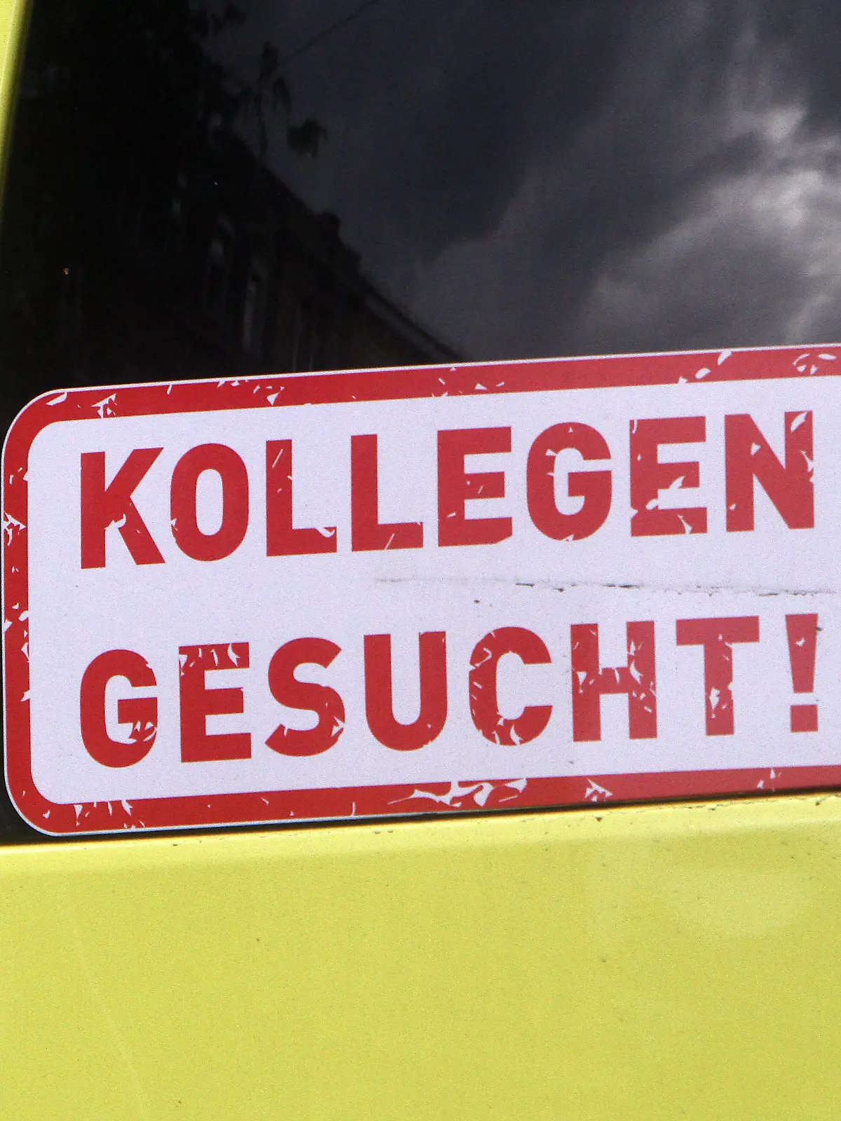  Aufkleber mit Aufschrift Kollegen gesucht klebt am Rückfenster eines Krankentransportwagen s in der Innenstadt von Heidelberg, Baden Württemberg, Deutschland *** Sticker with the inscription Colleagues wanted is stuck on the back window of an ambulance in downtown Heidelberg, Baden Württemberg, Germany