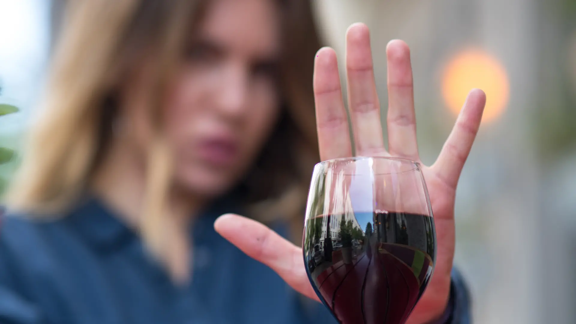 Junge Frau lehnt ein Glas Wein ab (Symbolfoto)