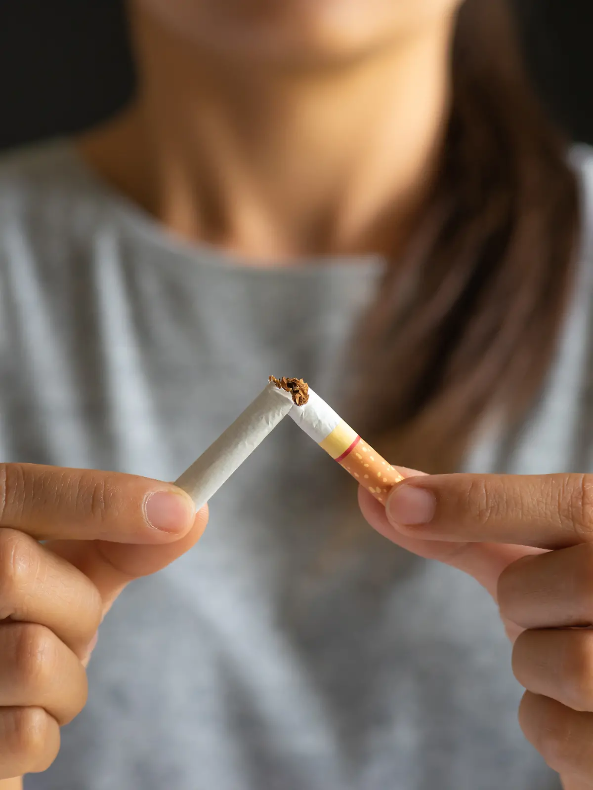 Nahaufname einer Zigarette, die von Frauenhänden zerbrochen wird