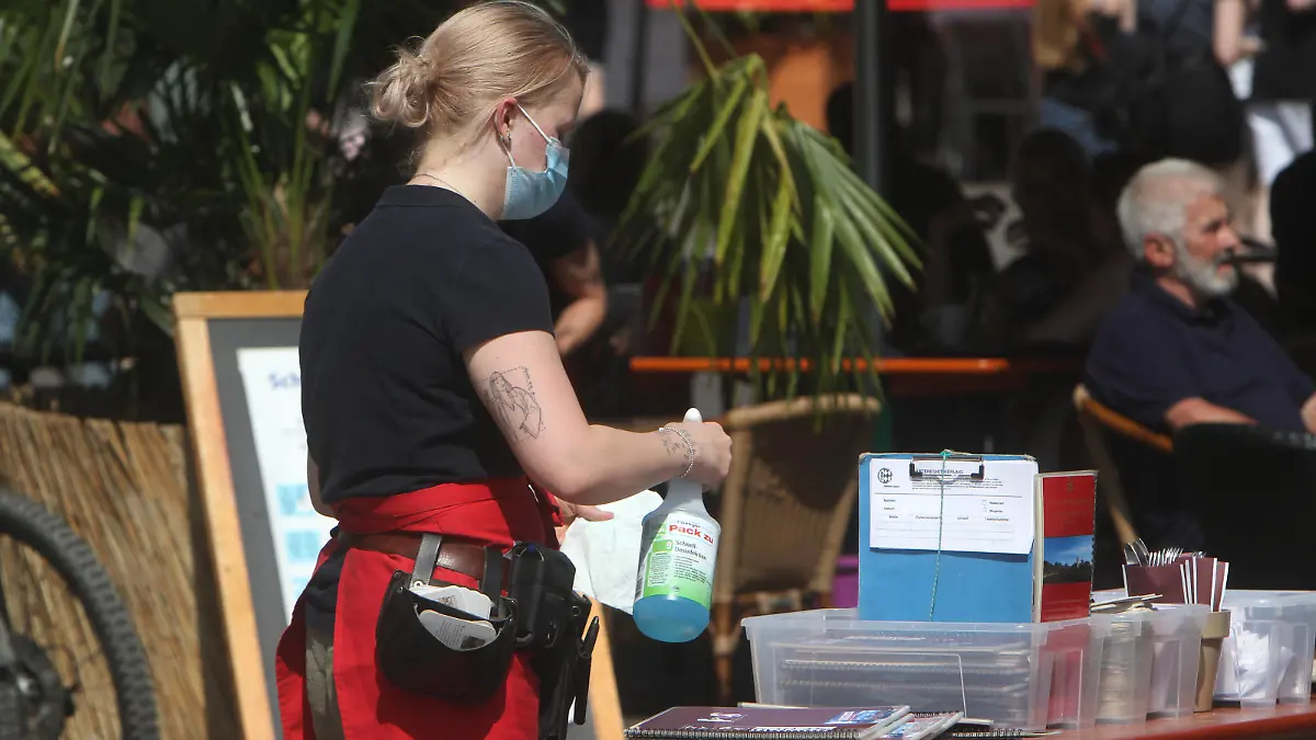 Aufgrund anhaltend niedriger Inzidenzen in Würzburg dürfen gastronomische Betriebe ihren Außenbereich auch ohne negativen Coronatest wieder öffnen. Eine Kellnerin eines Restaurants in der Innenstadt reinigt und desinfiziert Speisekarten am Hygienetisch, Bayern, Deutschland *** Due to persistently low incidences in Würzburg, gastronomic establishments are allowed to reopen their outdoor areas even without a negative coronal test A waitress at a restaurant in the city centre cleans and disinfects menus at the hygiene table, Bavaria, Germany 