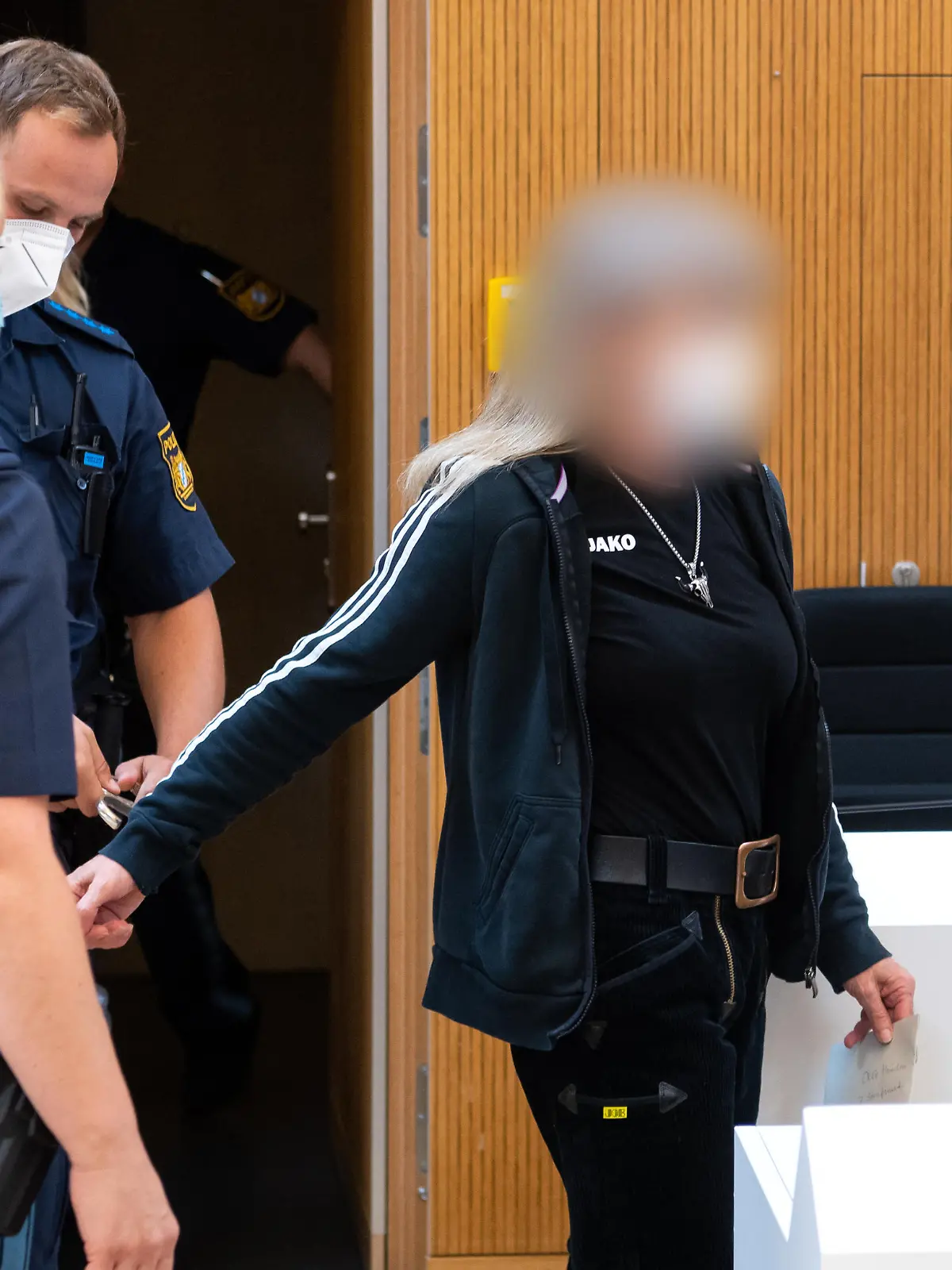 Der wegen Vorbereitung einer schweren staatsgefährdenden Gewalttat Angeklagten (r) werden im Sitzungssaal die Handschellen abgenommen. Weil sie Politiker bedroht und einen Brandanschlag vorbereitet hat, muss die Rechtsterroristin aus Franken für sech