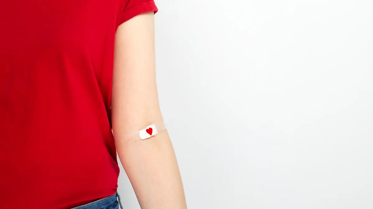 Frau mit Herzpflaster am Arm nach Blutspende.