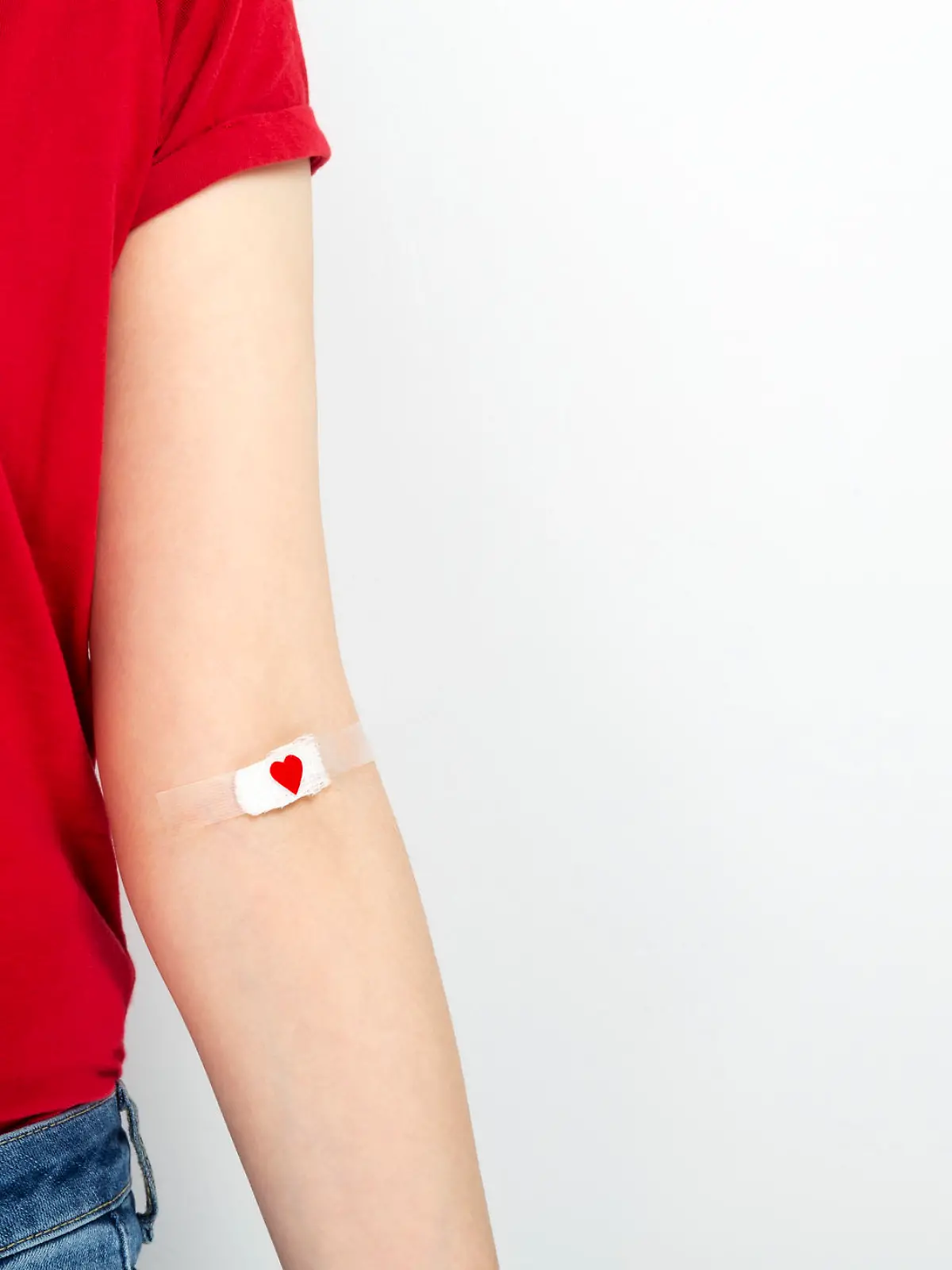 Frau mit Herzpflaster am Arm nach Blutspende.